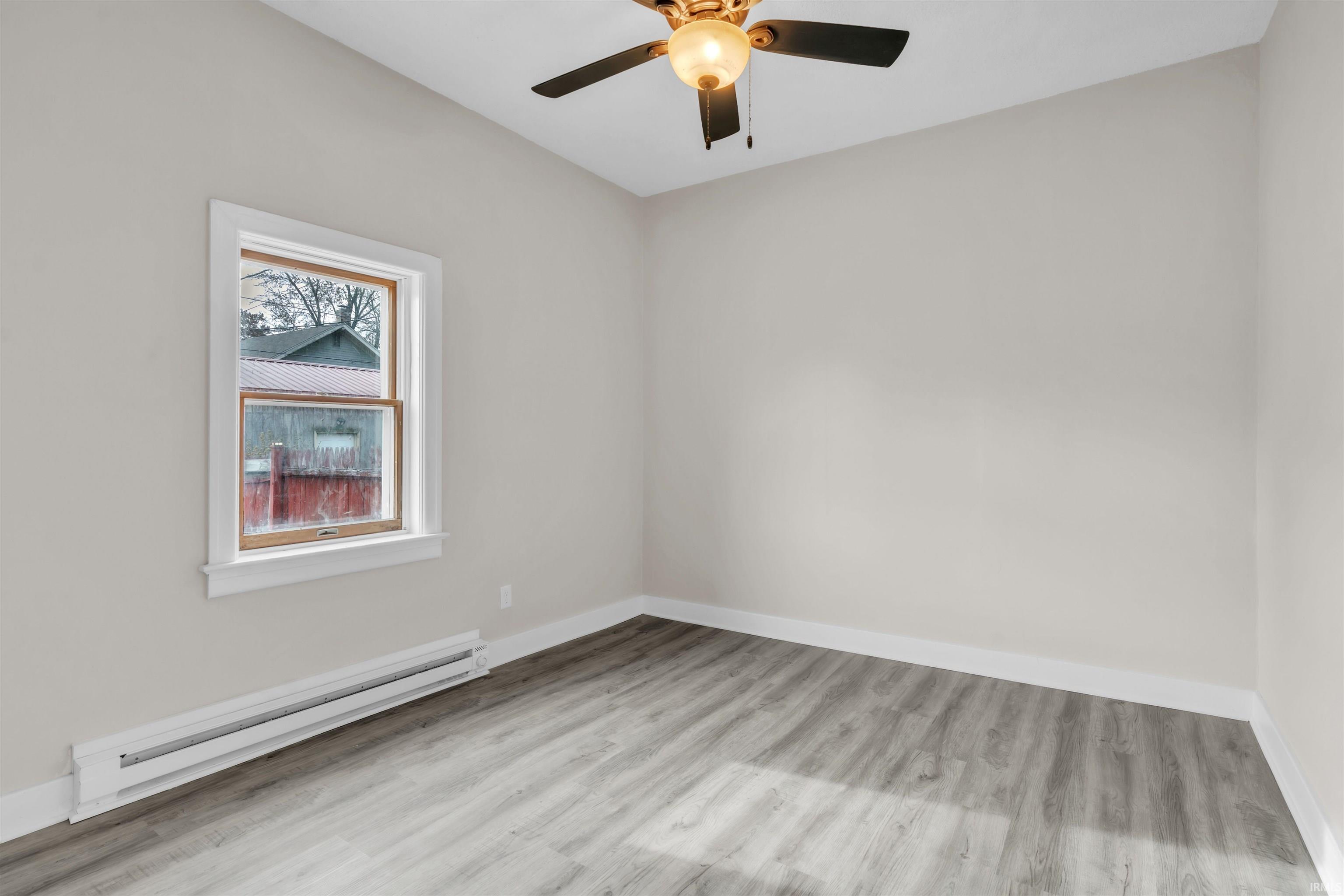 Unfurnished room with a baseboard heating unit and light wood-style flooring