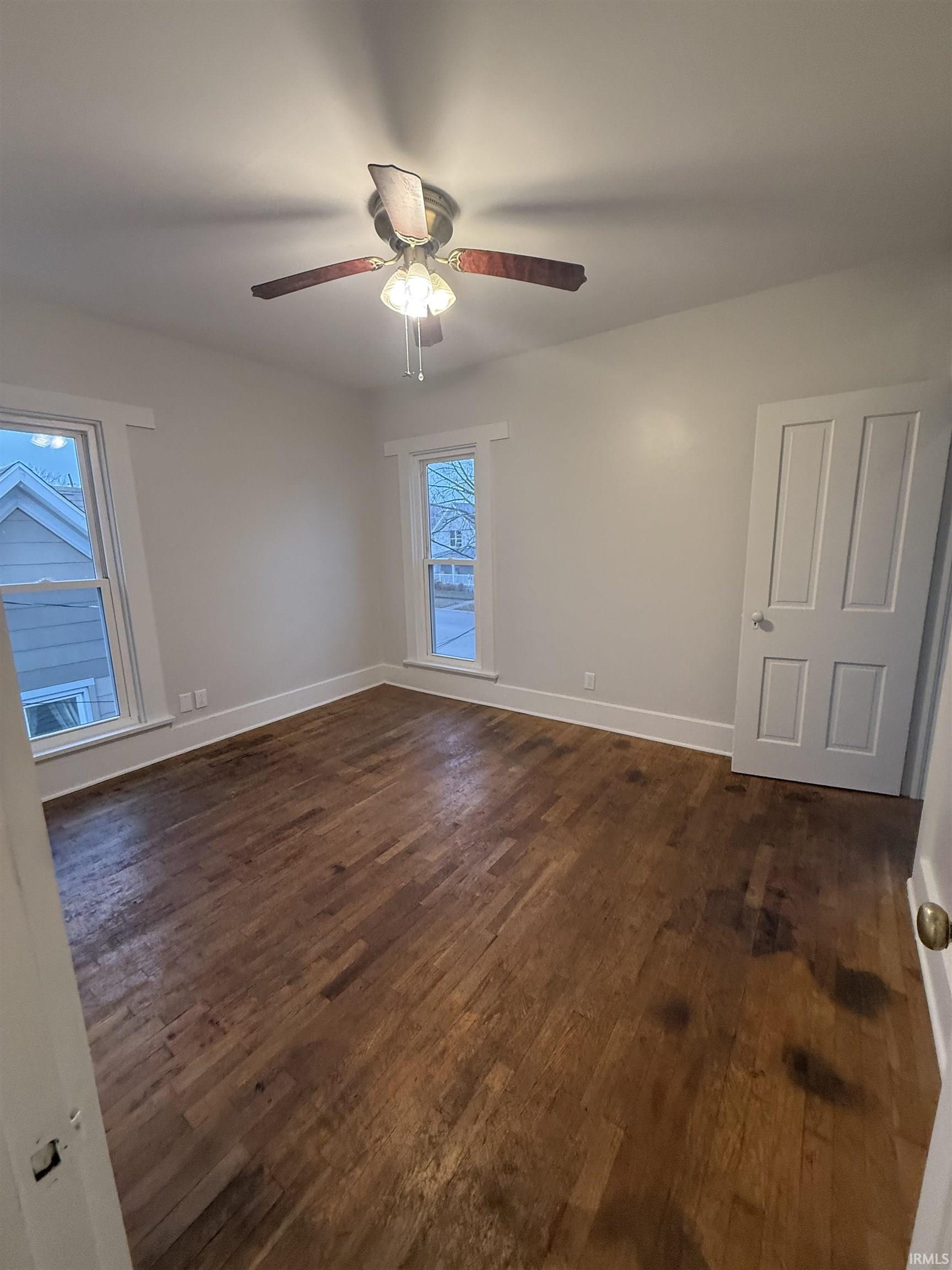 Spare room featuring dark wood-style flooring and a ceiling fan