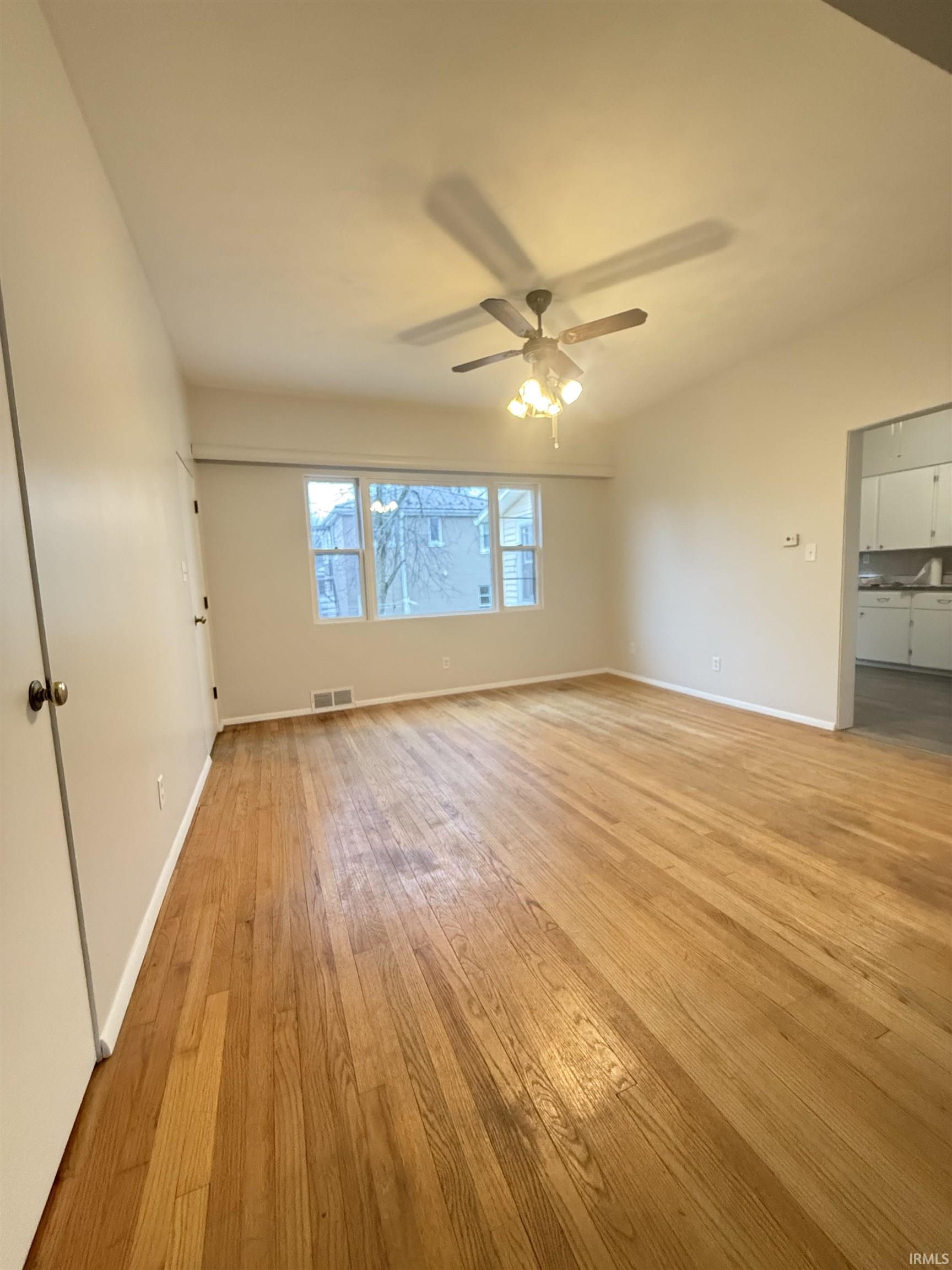 Unfurnished room with light wood-style flooring, ceiling fan, and vaulted ceiling