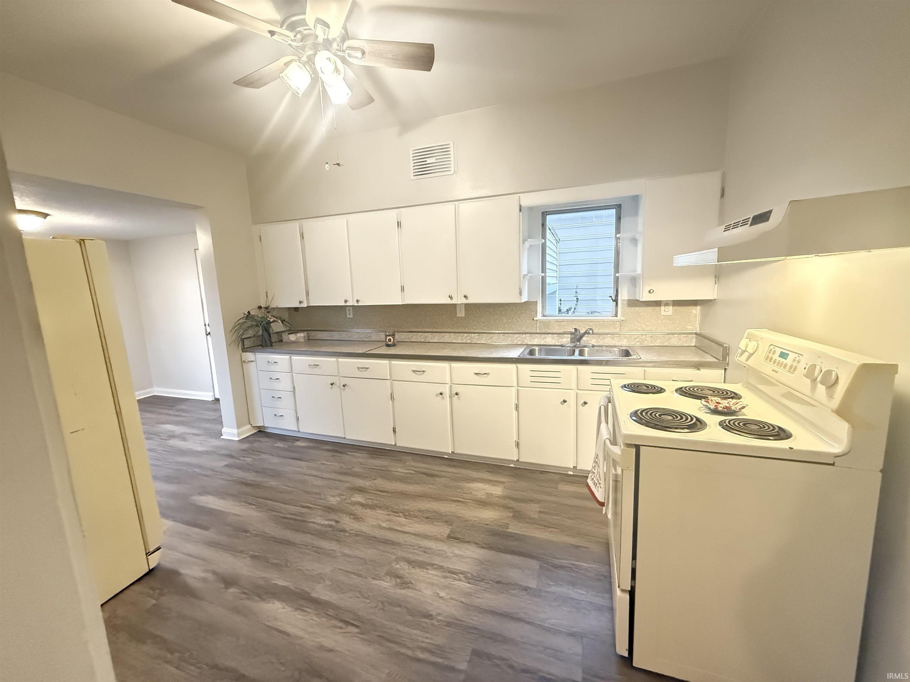 Kitchen with white appliances, exhaust hood, dark wood-style floors, a ceiling fan, and white cabinets