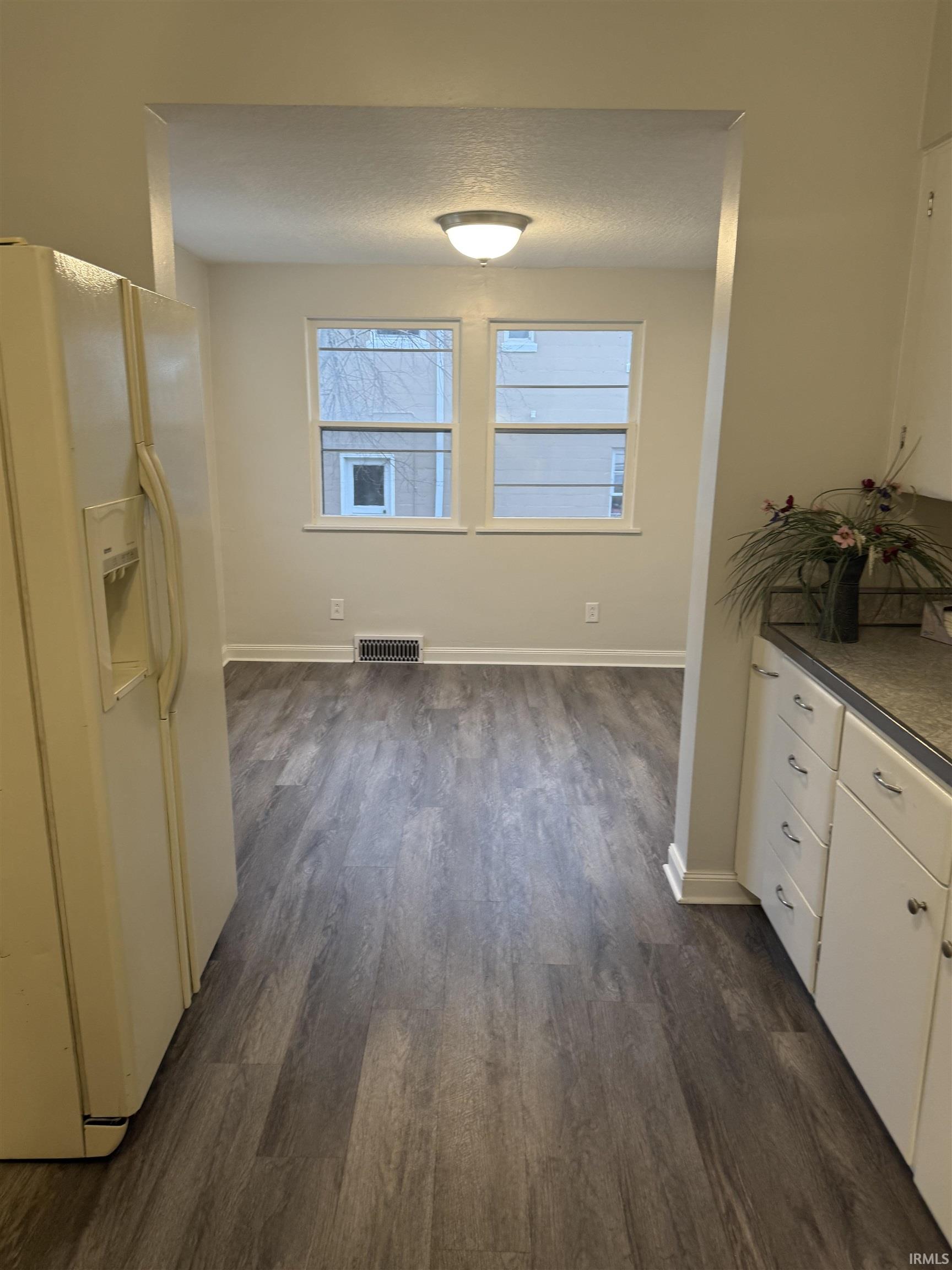 Unfurnished dining area featuring dark wood finished floors and a textured ceiling