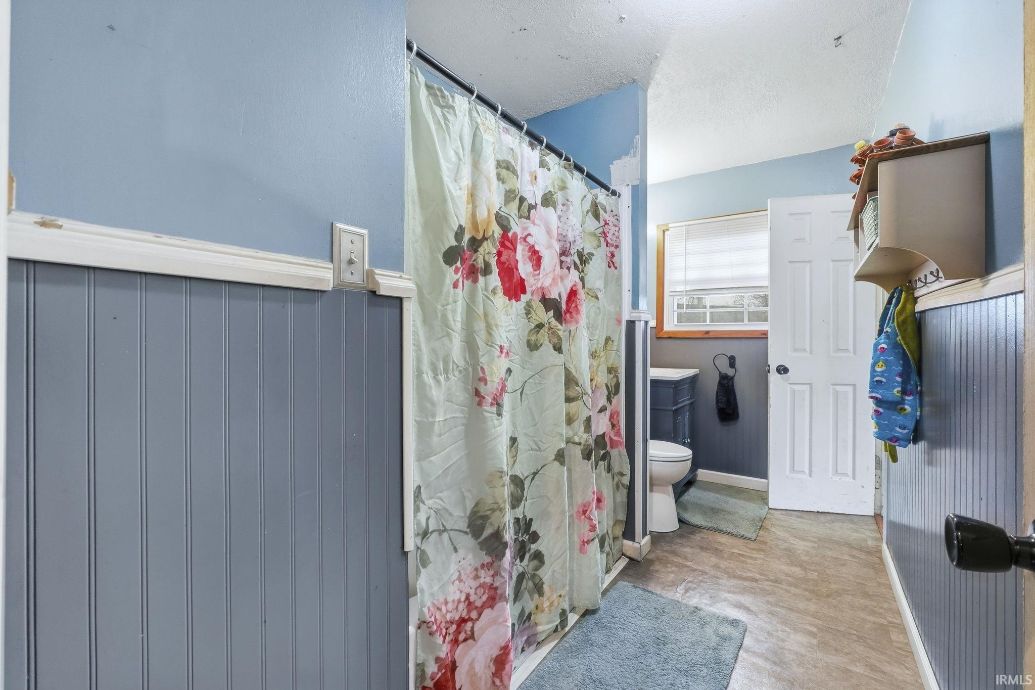 Bathroom featuring a shower with shower curtain and baseboards