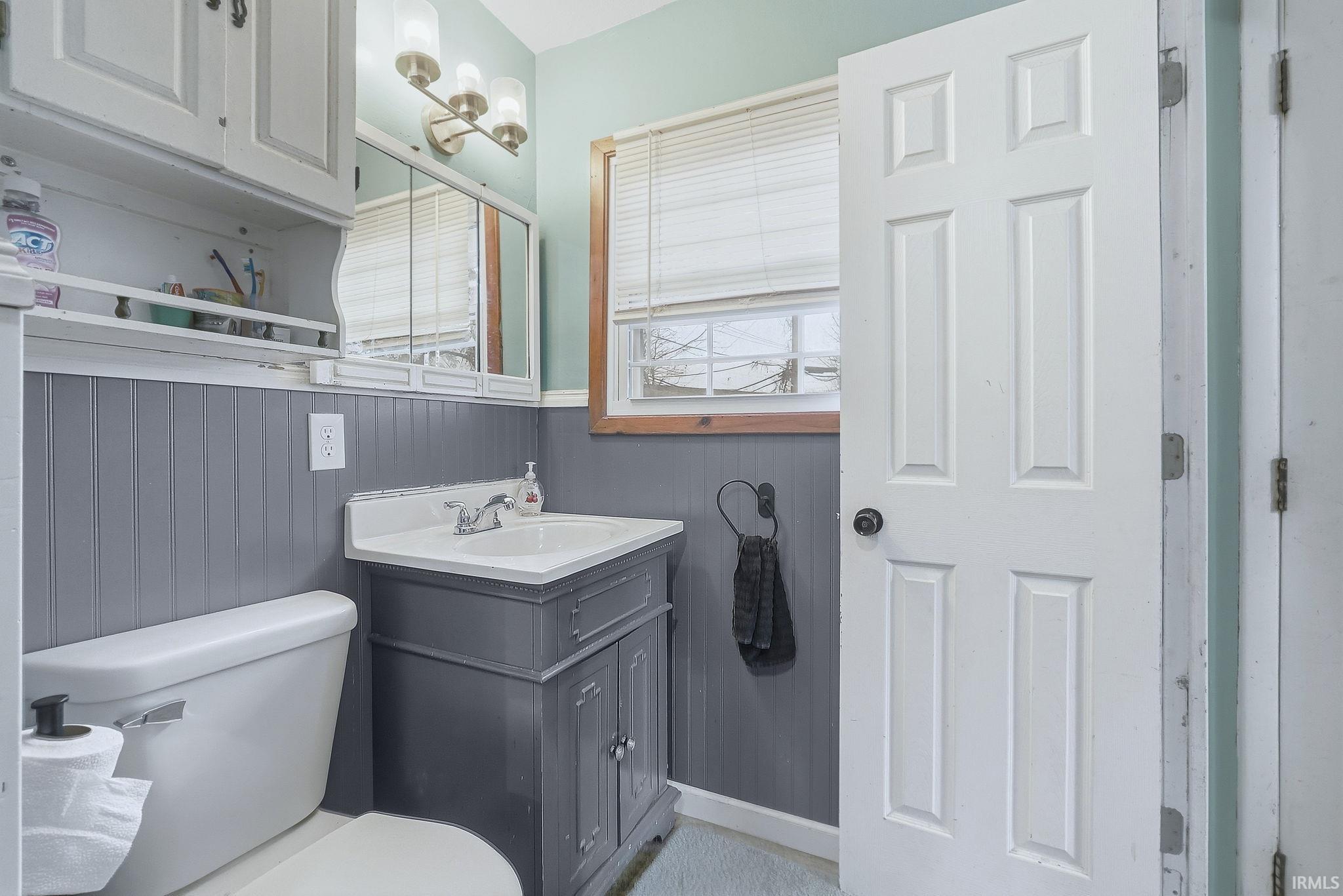 Bathroom featuring a wainscoted wall, vanity, and wooden walls
