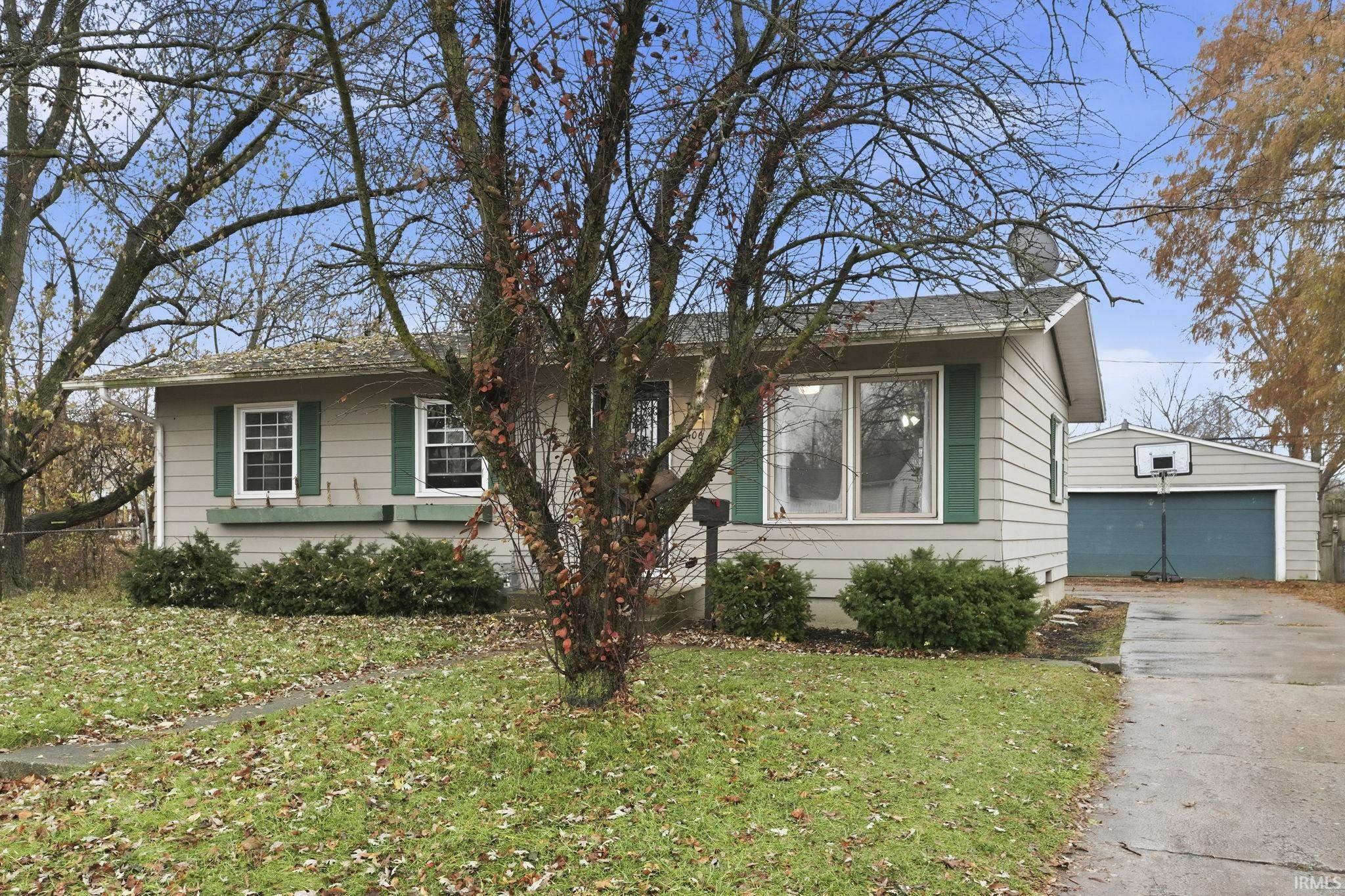 Bungalow-style house featuring an outbuilding, a garage, a front lawn, and a chimney