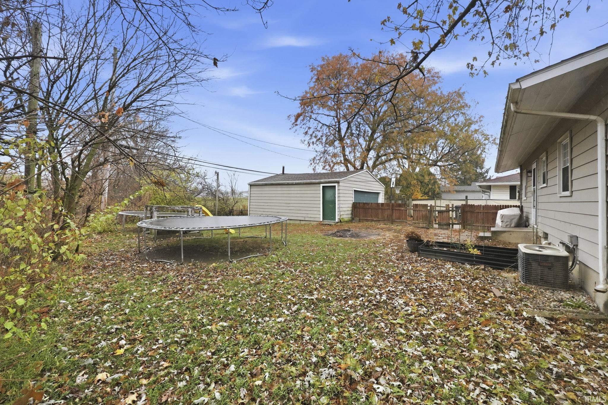 View of yard with a trampoline, an outbuilding, and a vegetable garden