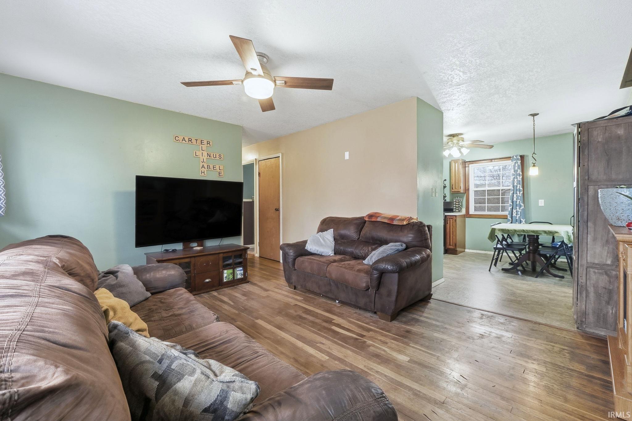Living area featuring ceiling fan, hardwood / wood-style floors, and a textured ceiling