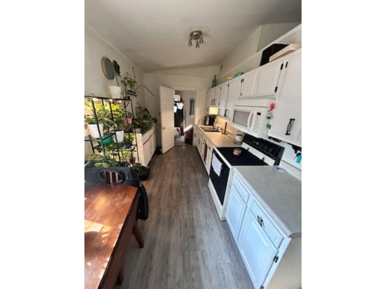 Kitchen featuring light countertops, white appliances, vaulted ceiling, white cabinets, and dark wood-style flooring