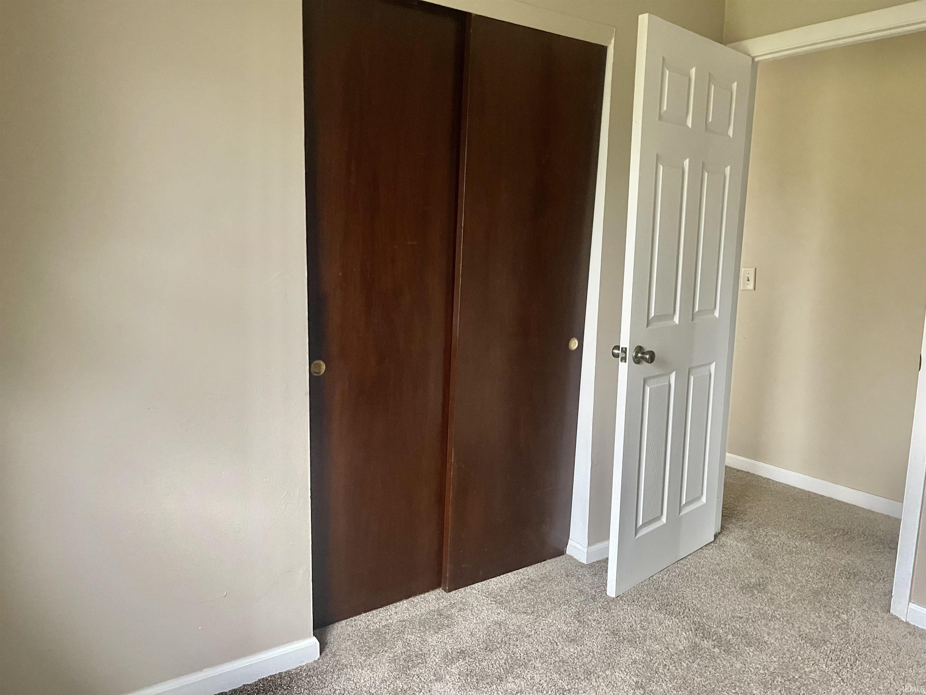 Unfurnished bedroom with light colored carpet and a closet