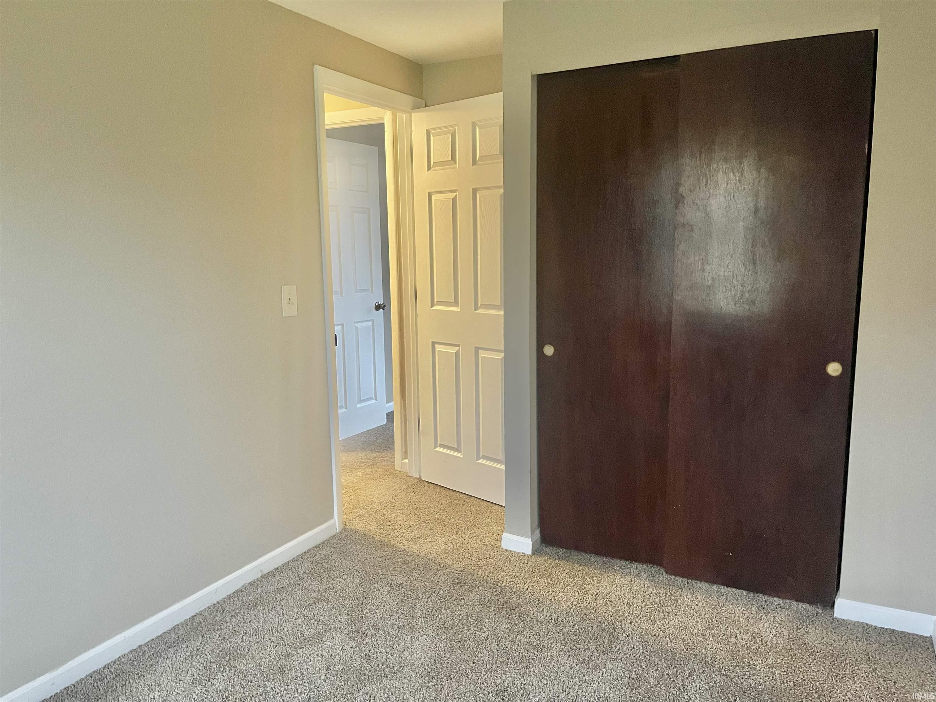 Unfurnished bedroom featuring a closet and light colored carpet