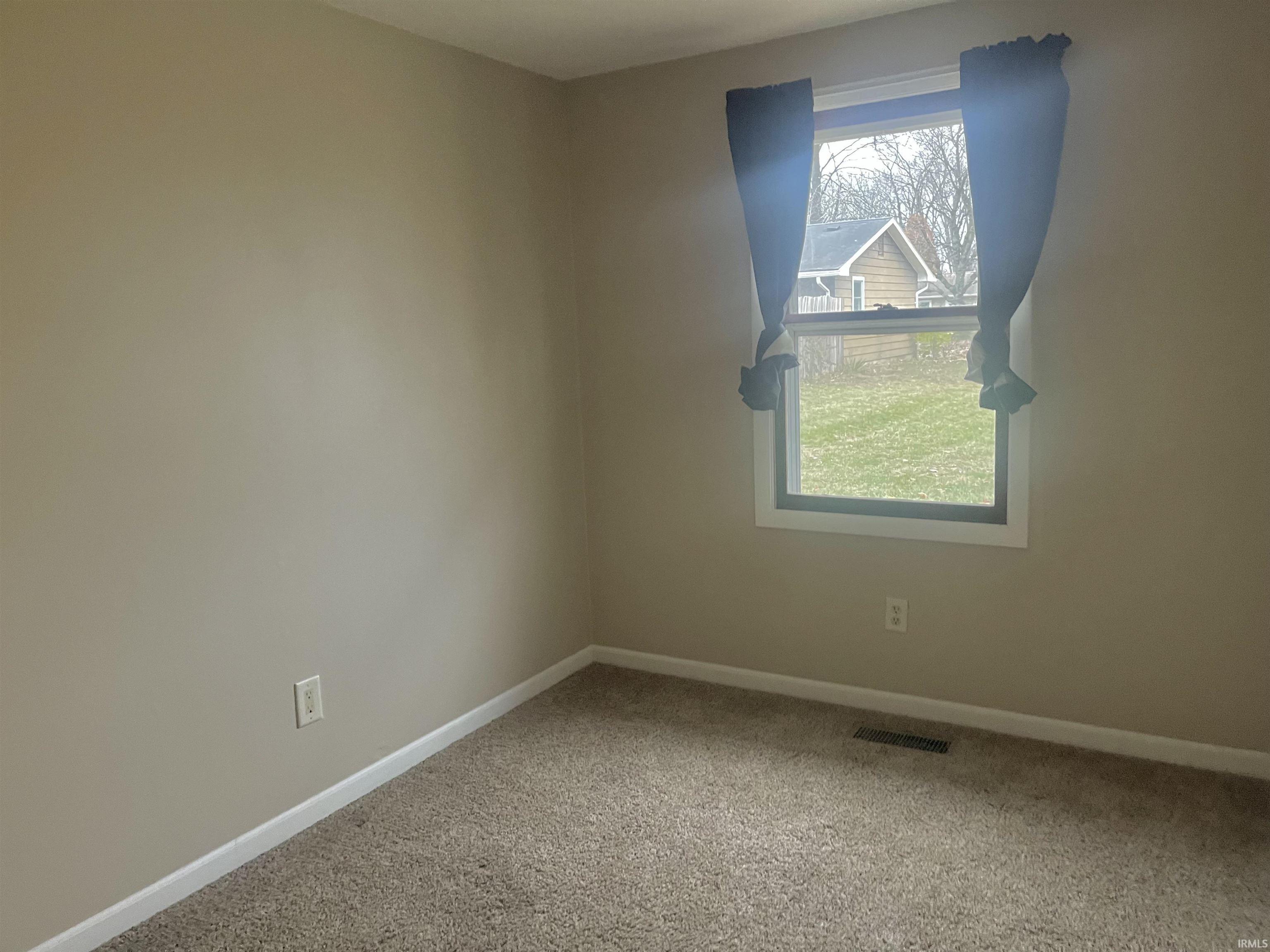 Carpeted spare room with baseboards
