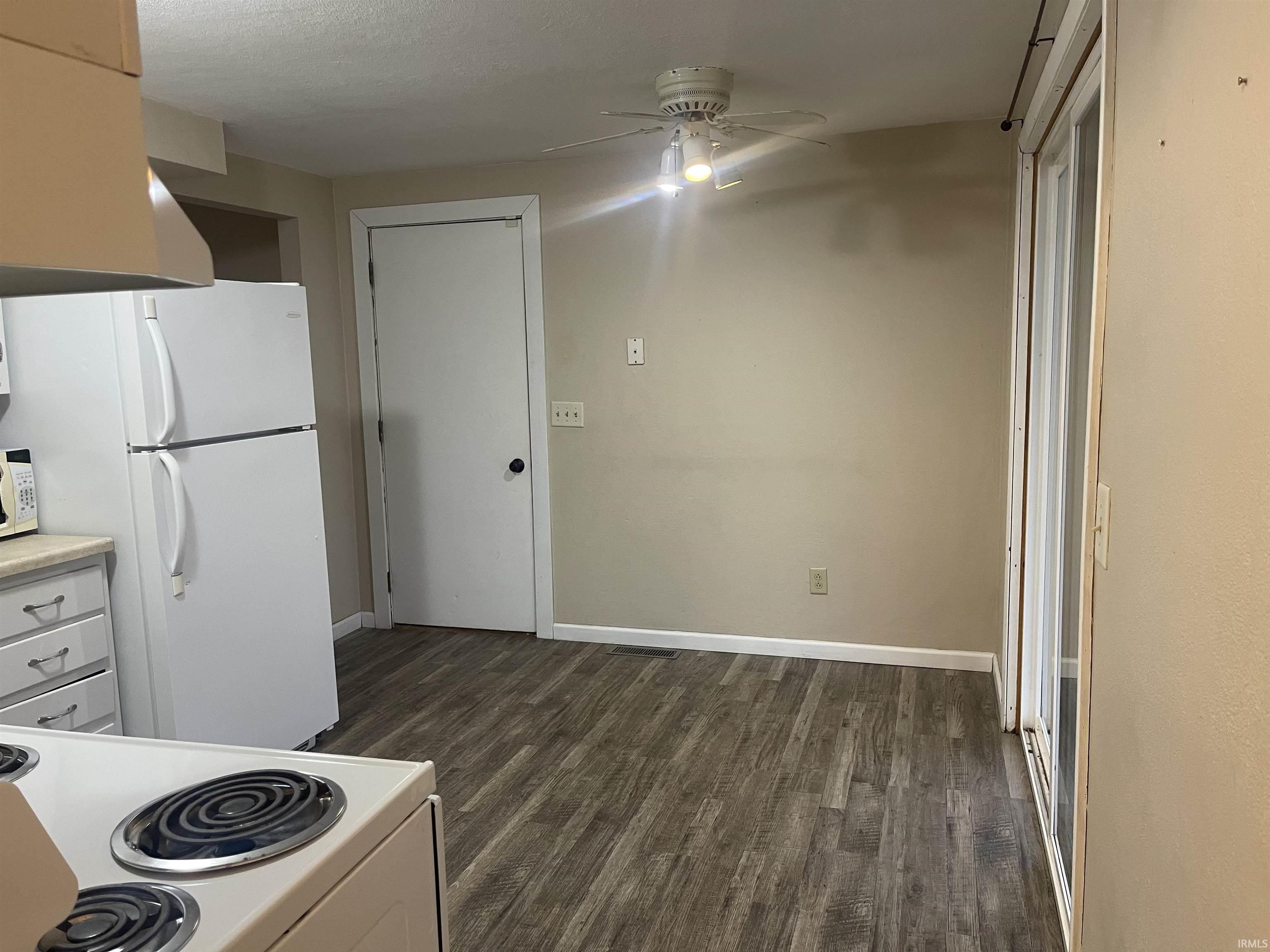 Kitchen with white appliances, light countertops, dark wood-type flooring, and a ceiling fan