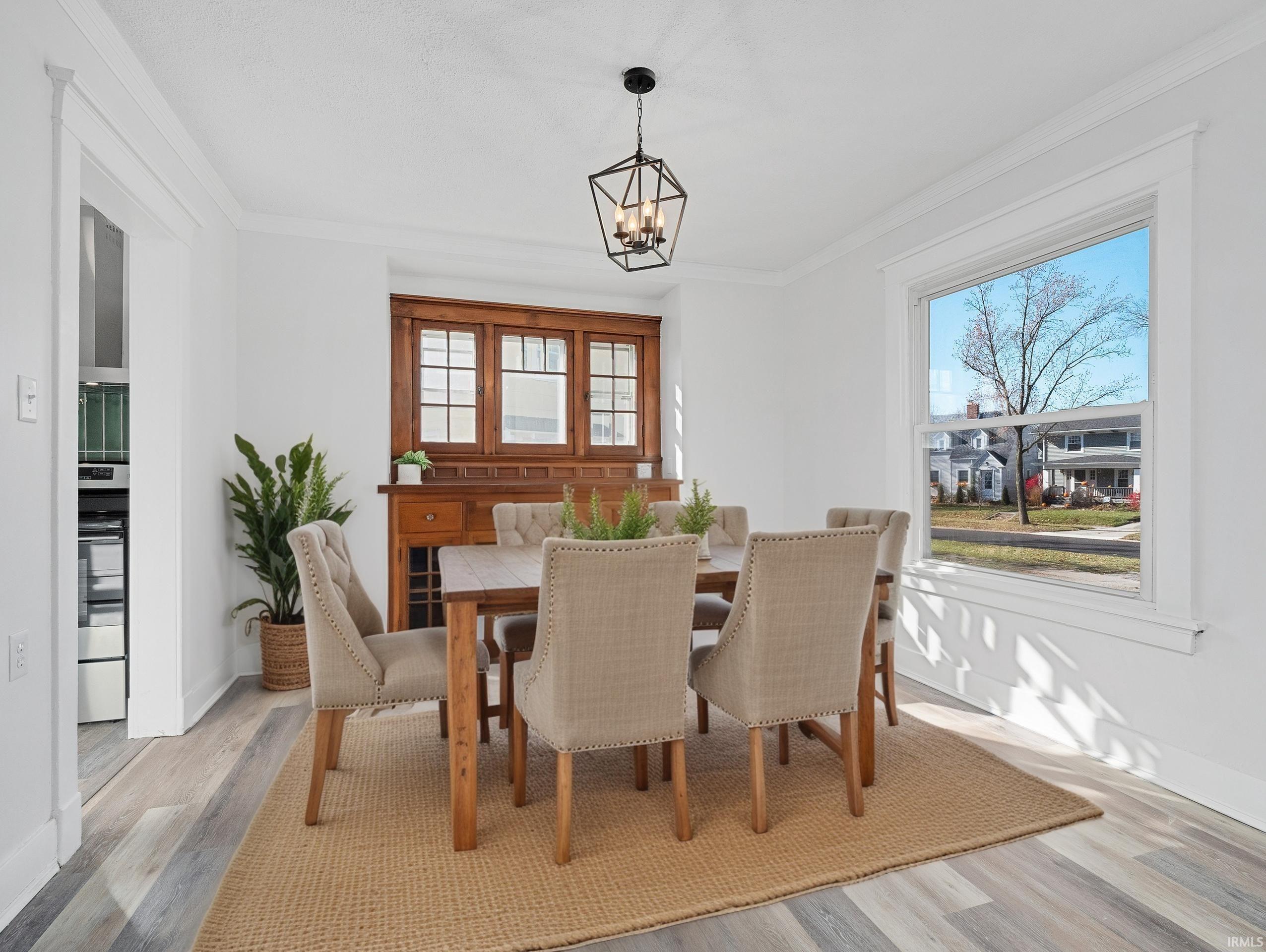Dining area featuring ornamental molding, light wood-type flooring, and a chandelier