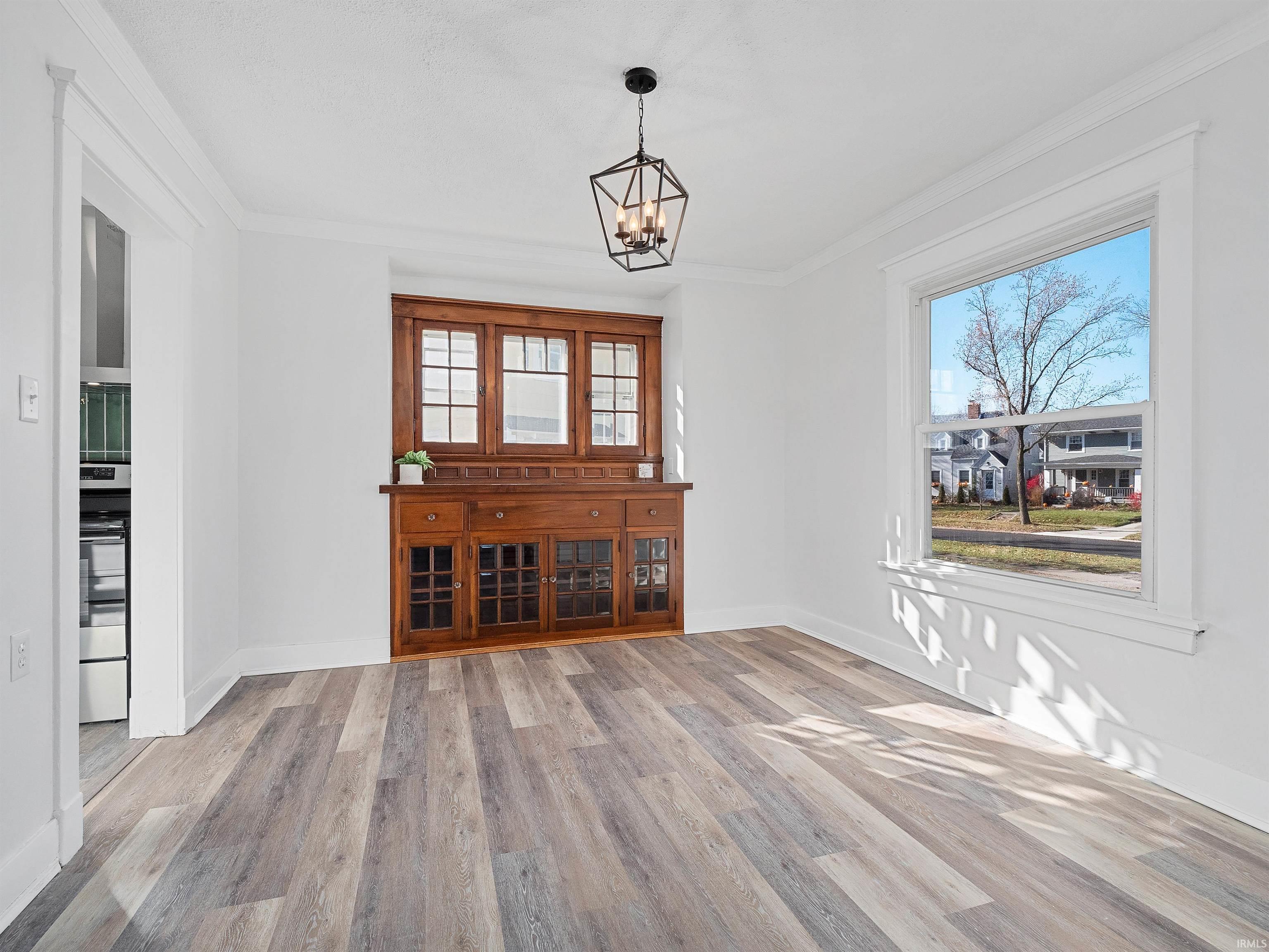 Unfurnished dining area featuring ornamental molding, light wood finished floors, and a chandelier