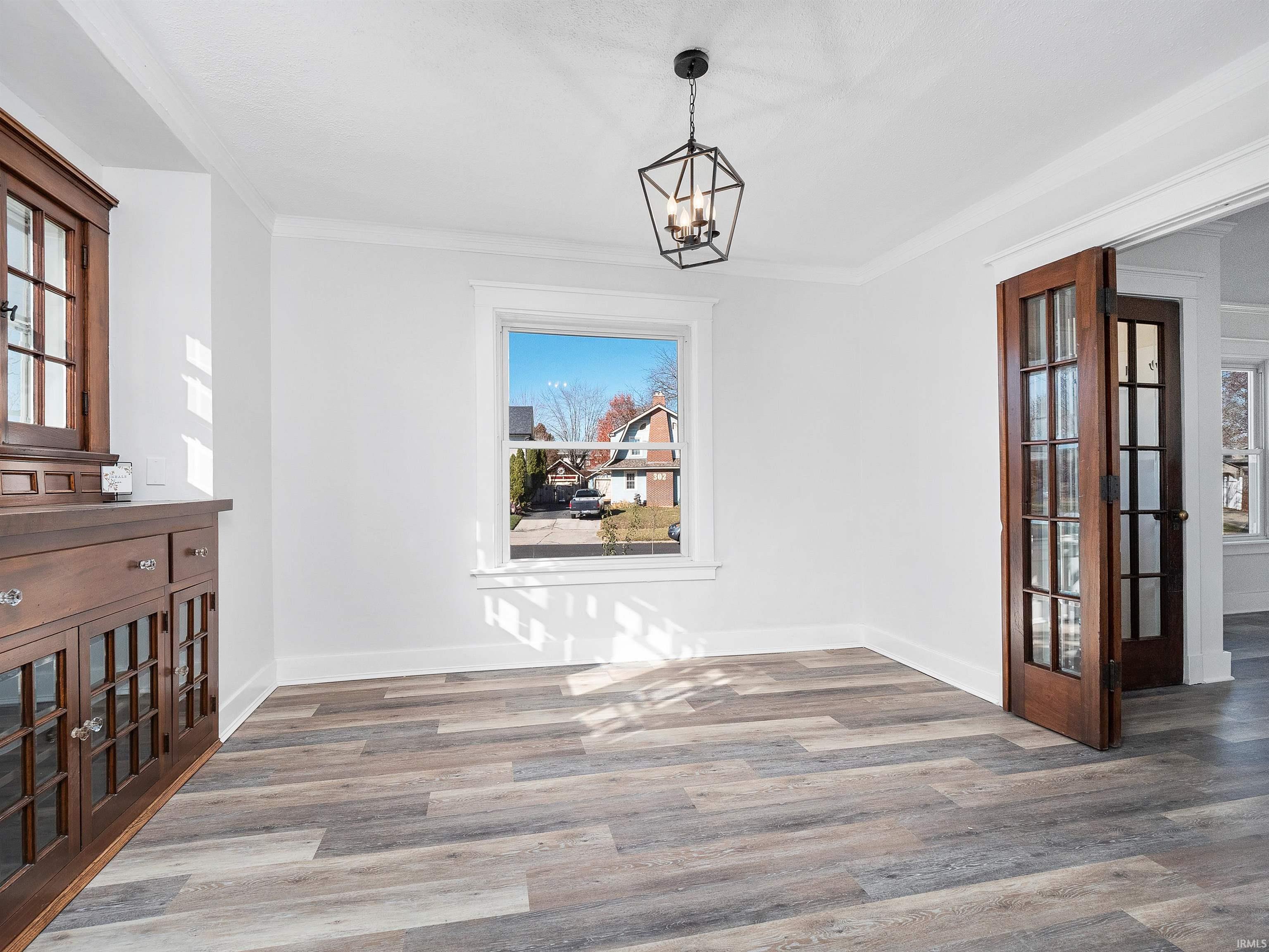Unfurnished dining area with plenty of natural light, wood finished floors, crown molding, and a chandelier