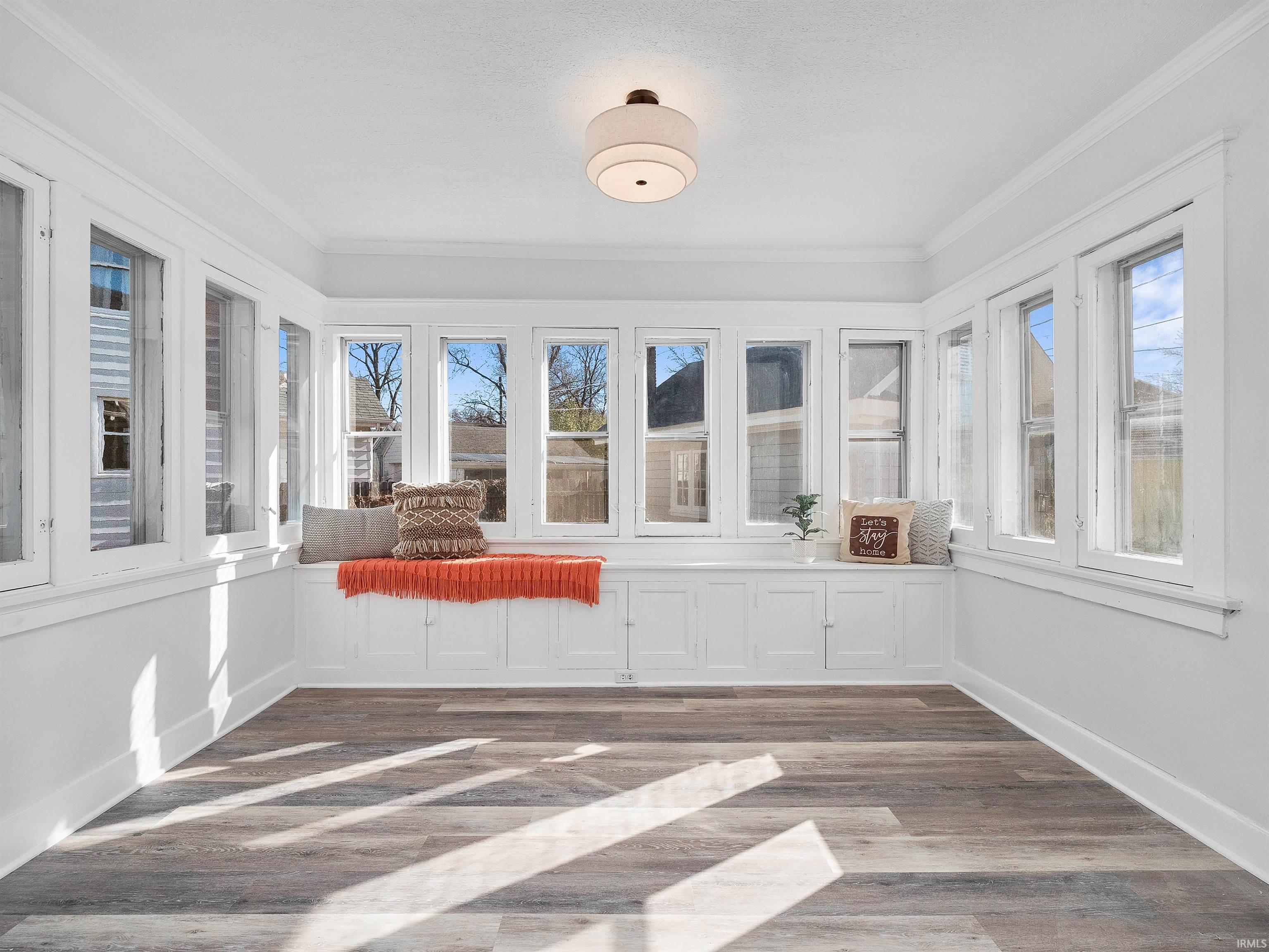 Unfurnished sunroom featuring wood finished floors and ornamental molding