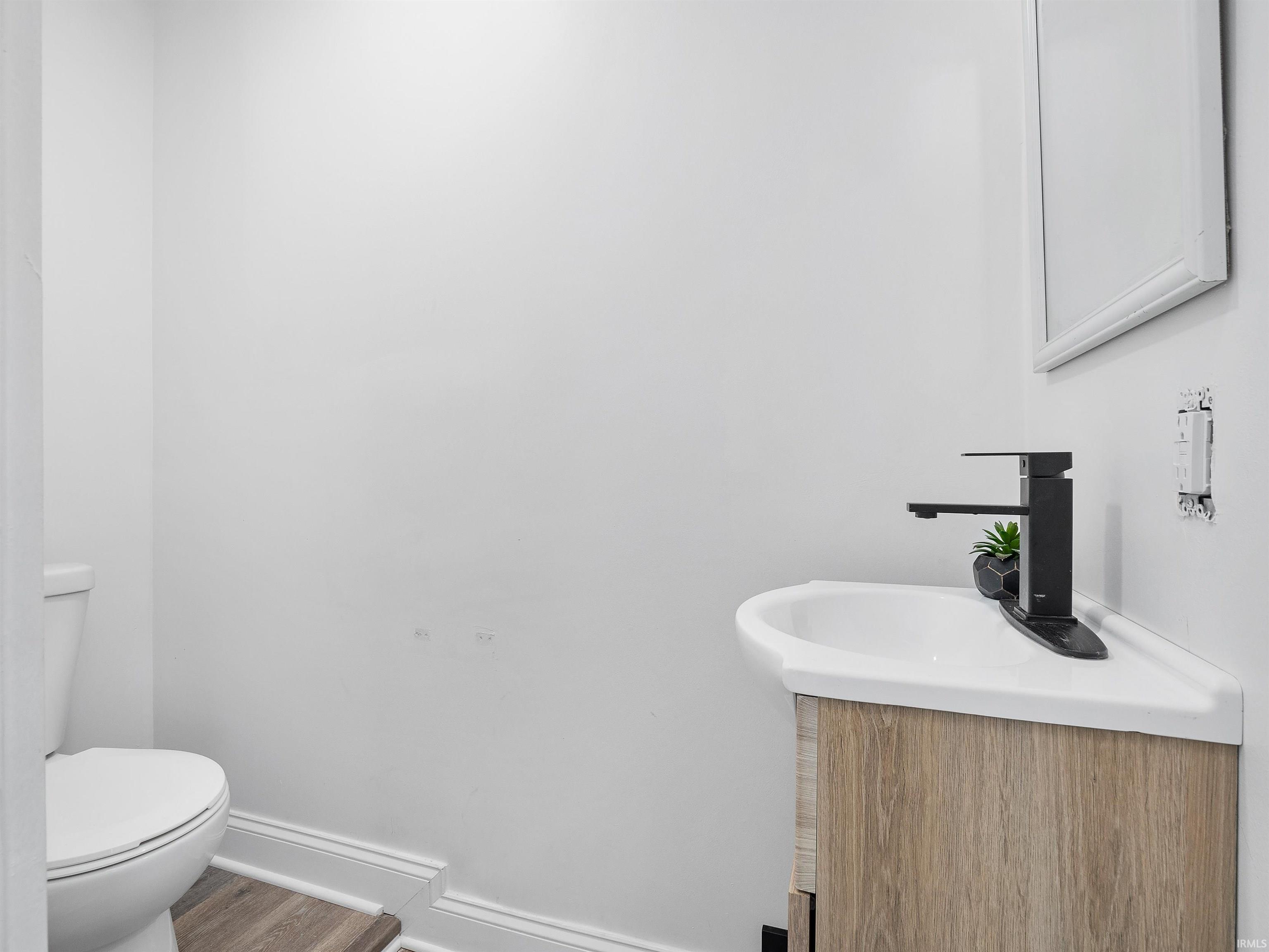 Half bathroom featuring vanity and wood finished floors