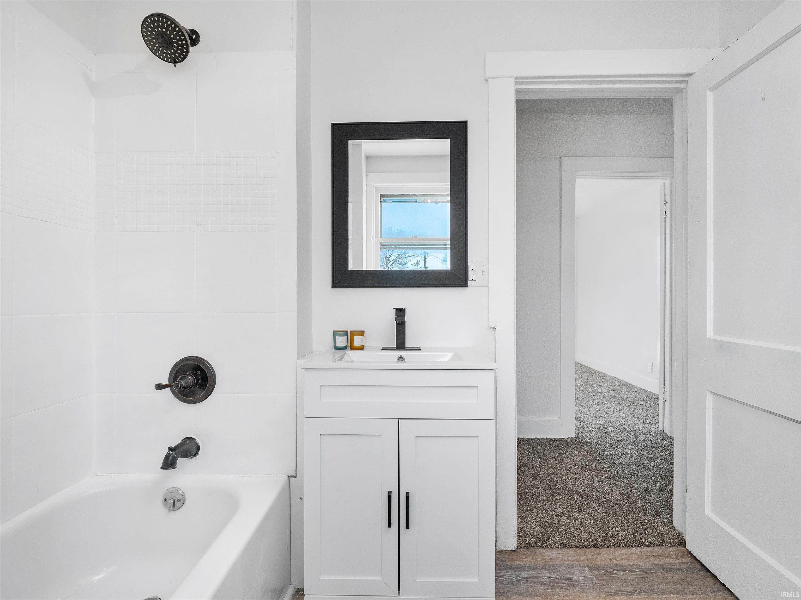 Bathroom featuring vanity, shower / bath combination, and dark wood-type flooring