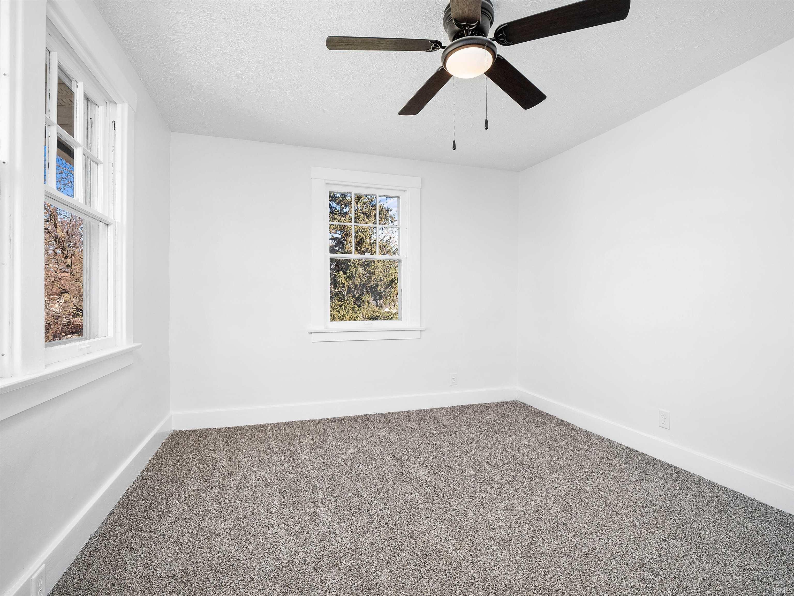 Carpeted empty room featuring baseboards and a ceiling fan