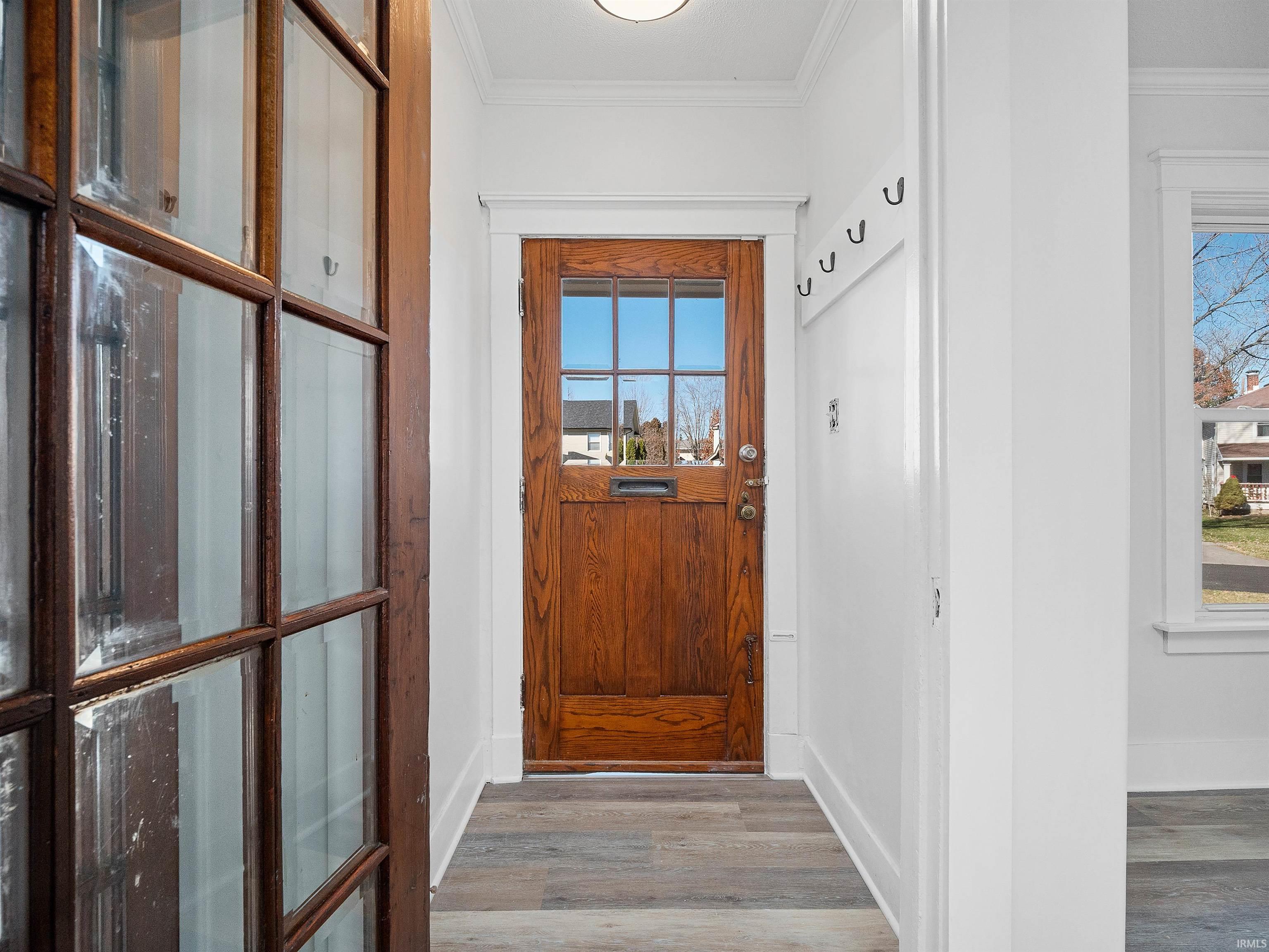 Doorway to outside with ornamental molding and wood finished floors