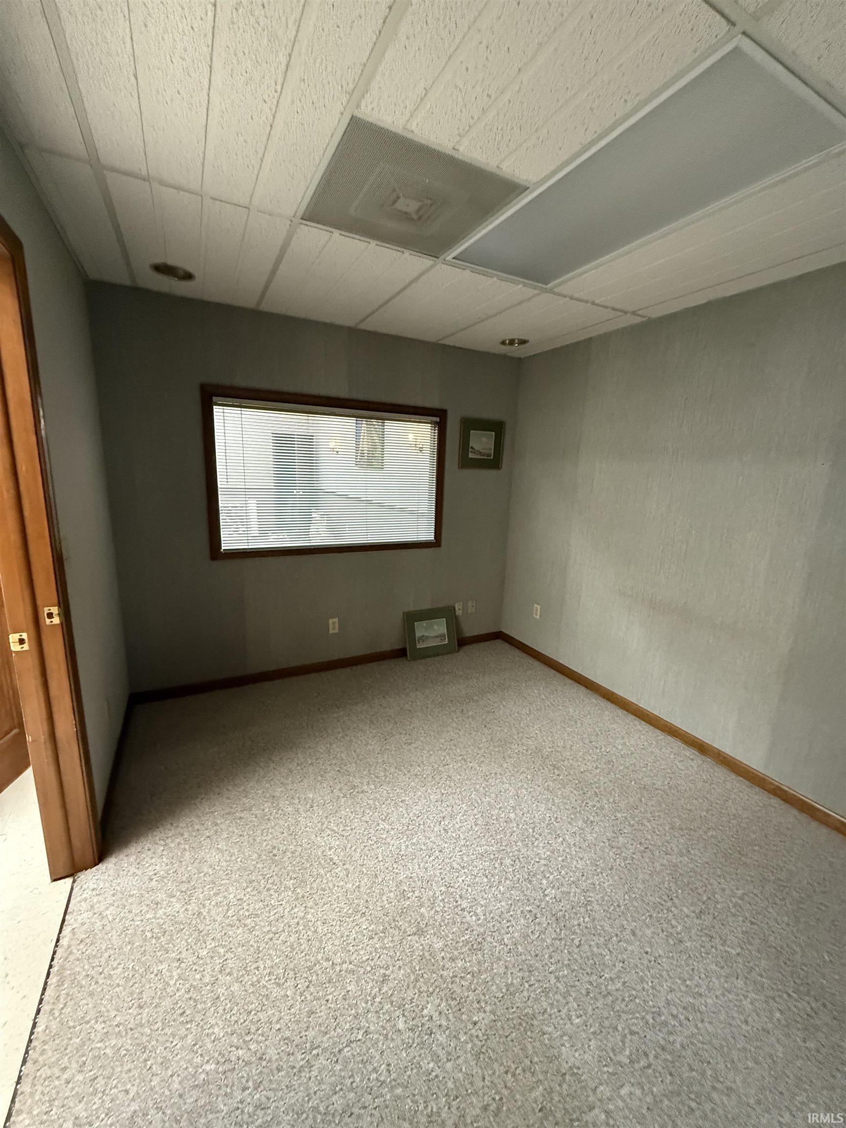 Carpeted empty room with a paneled ceiling and baseboards