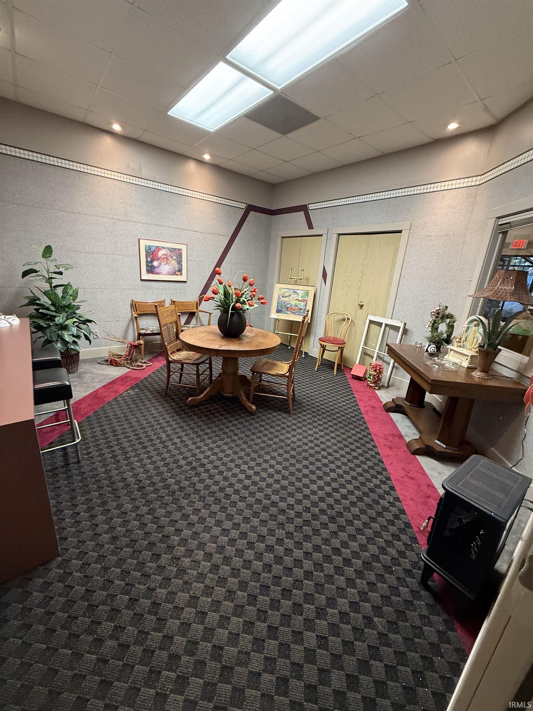 Dining room with a drop ceiling and dark colored carpet