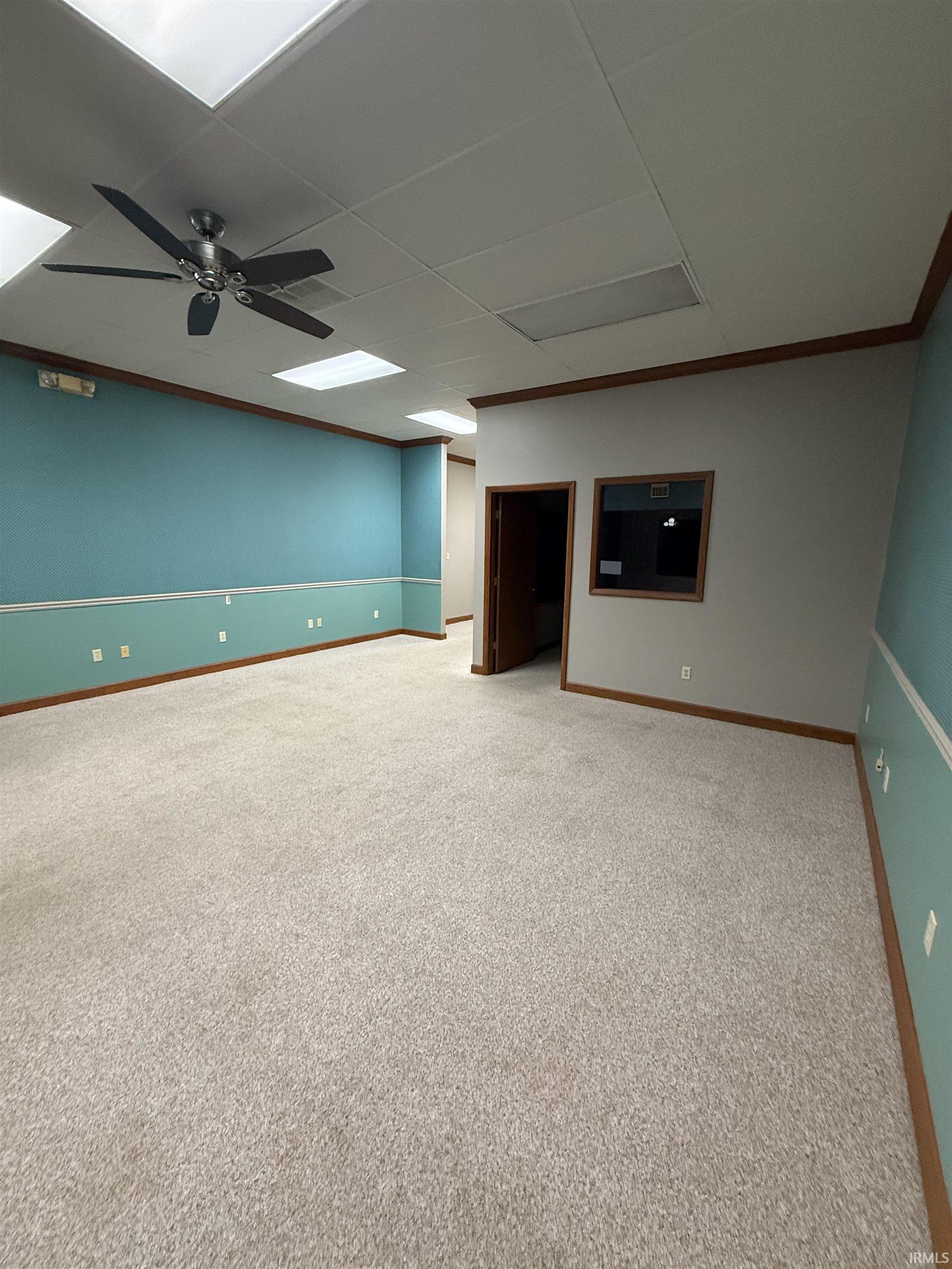 Carpeted empty room with a paneled ceiling and a ceiling fan