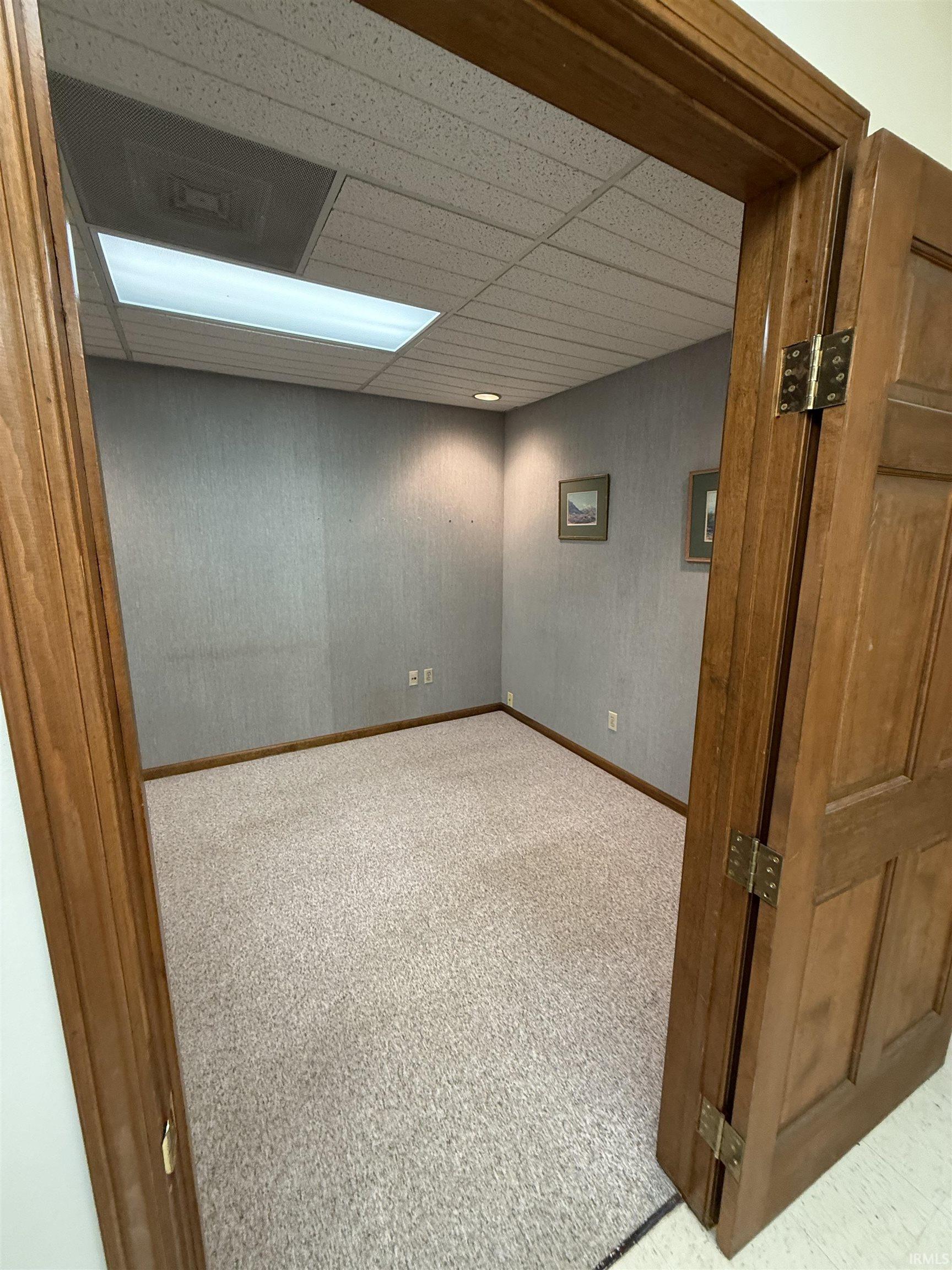 Empty room featuring a paneled ceiling and carpet floors
