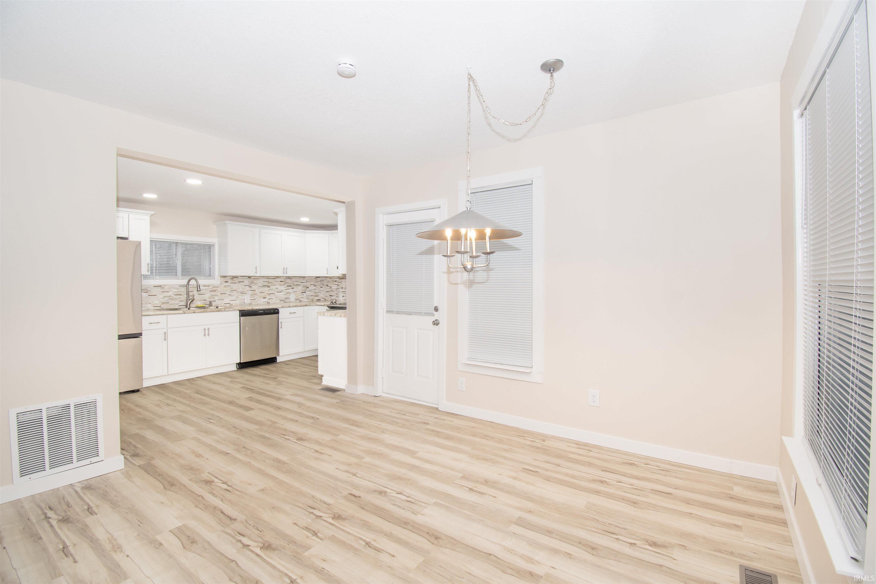 Unfurnished dining area with light wood-style flooring and recessed lighting