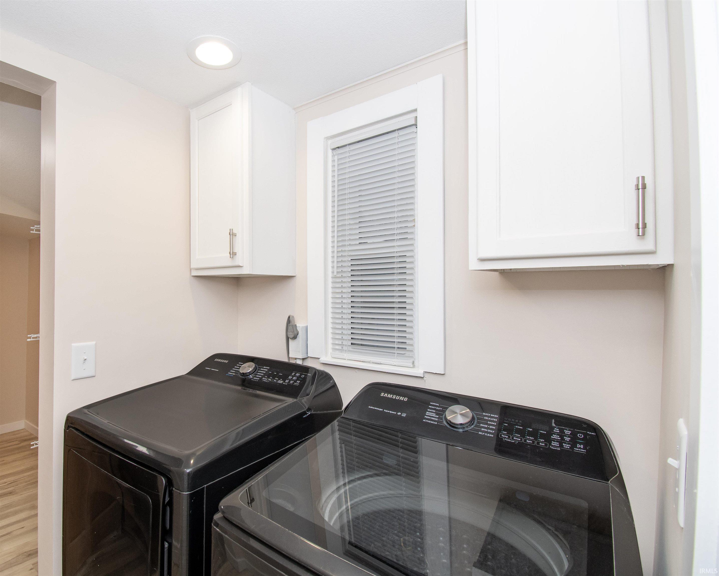 Washroom featuring independent washer and dryer, wood finished floors, and recessed lighting