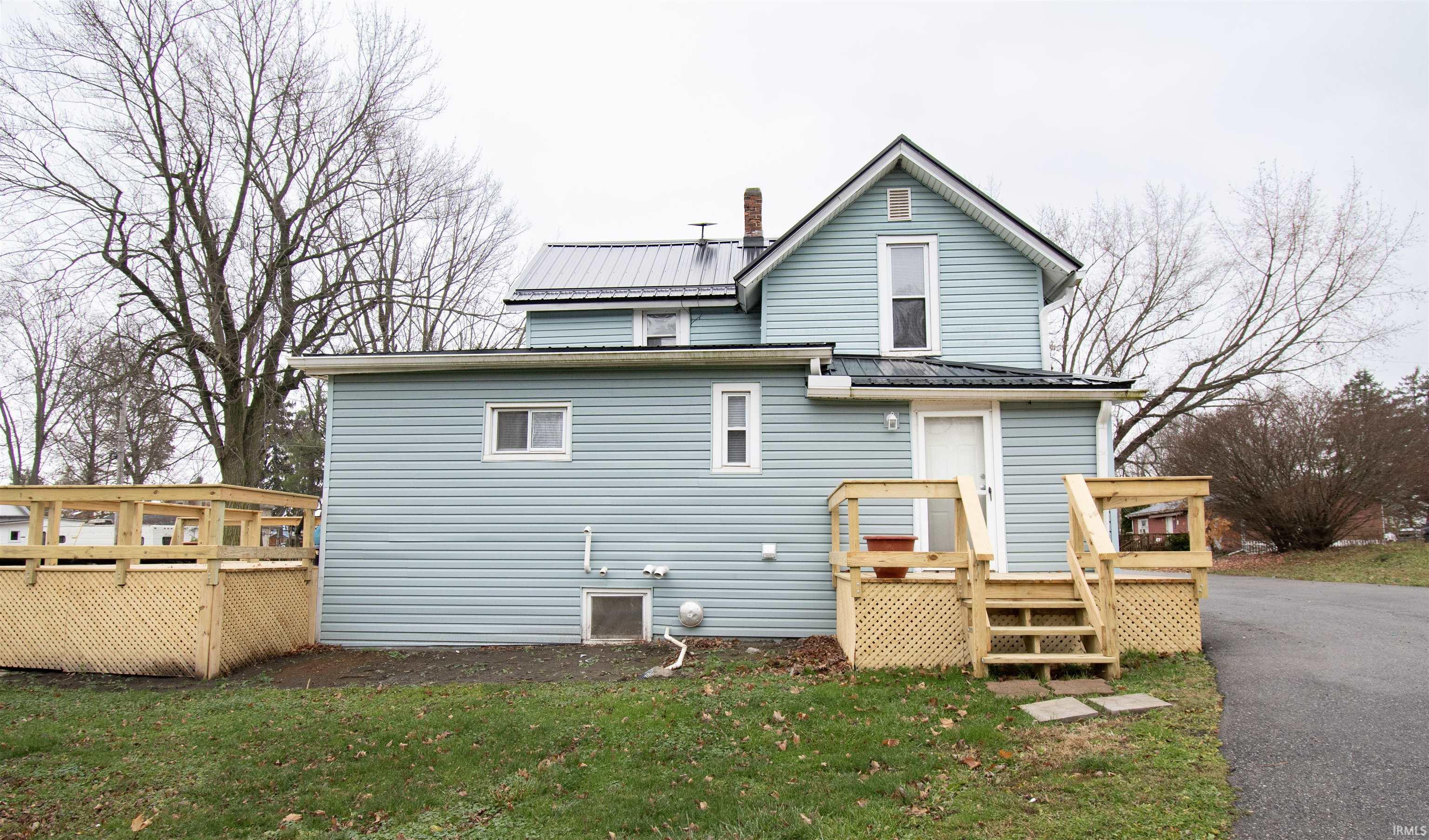 Rear view of house with a metal roof, a wooden deck, a yard, and a chimney