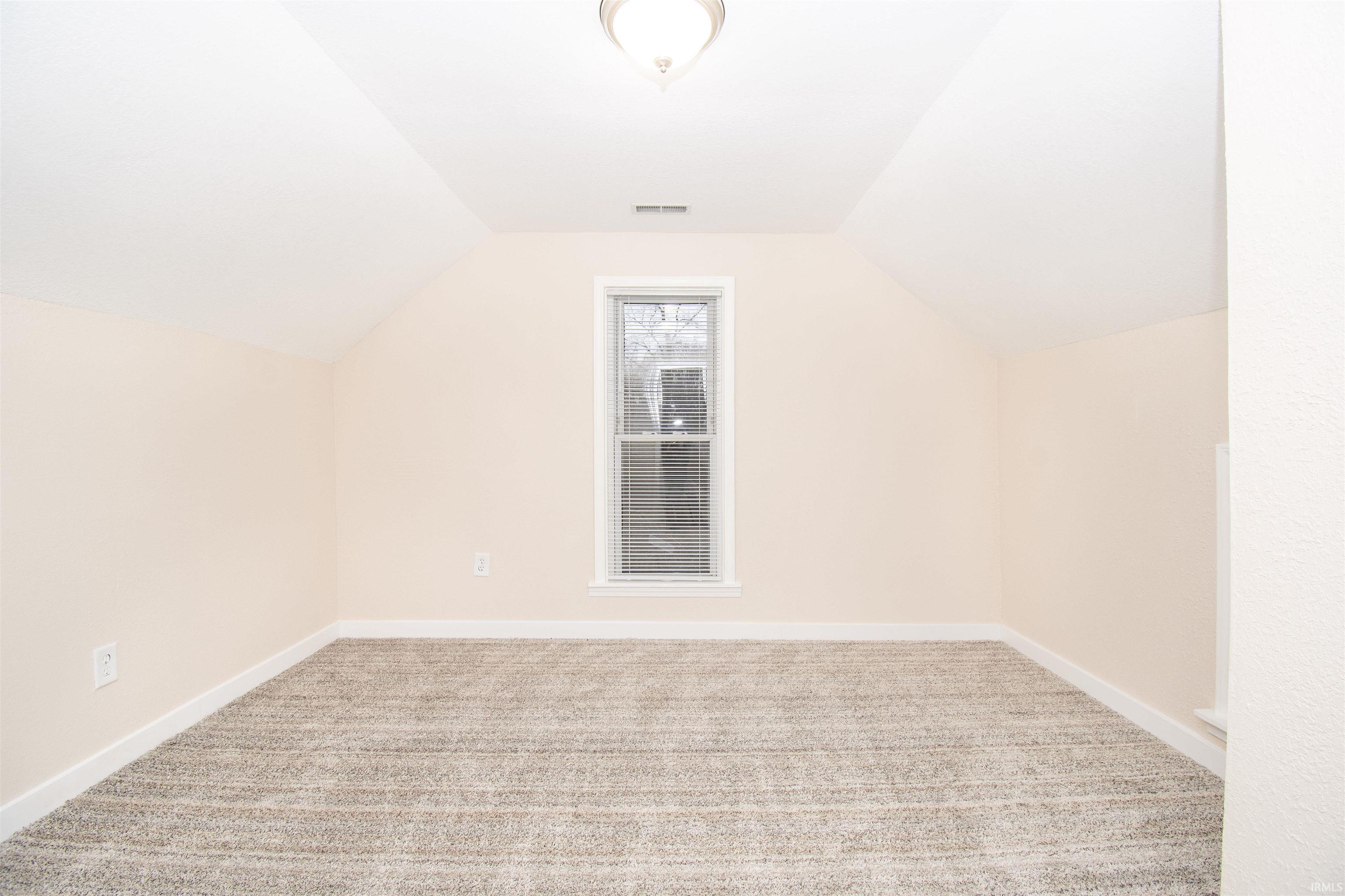 Additional living space featuring light carpet and lofted ceiling