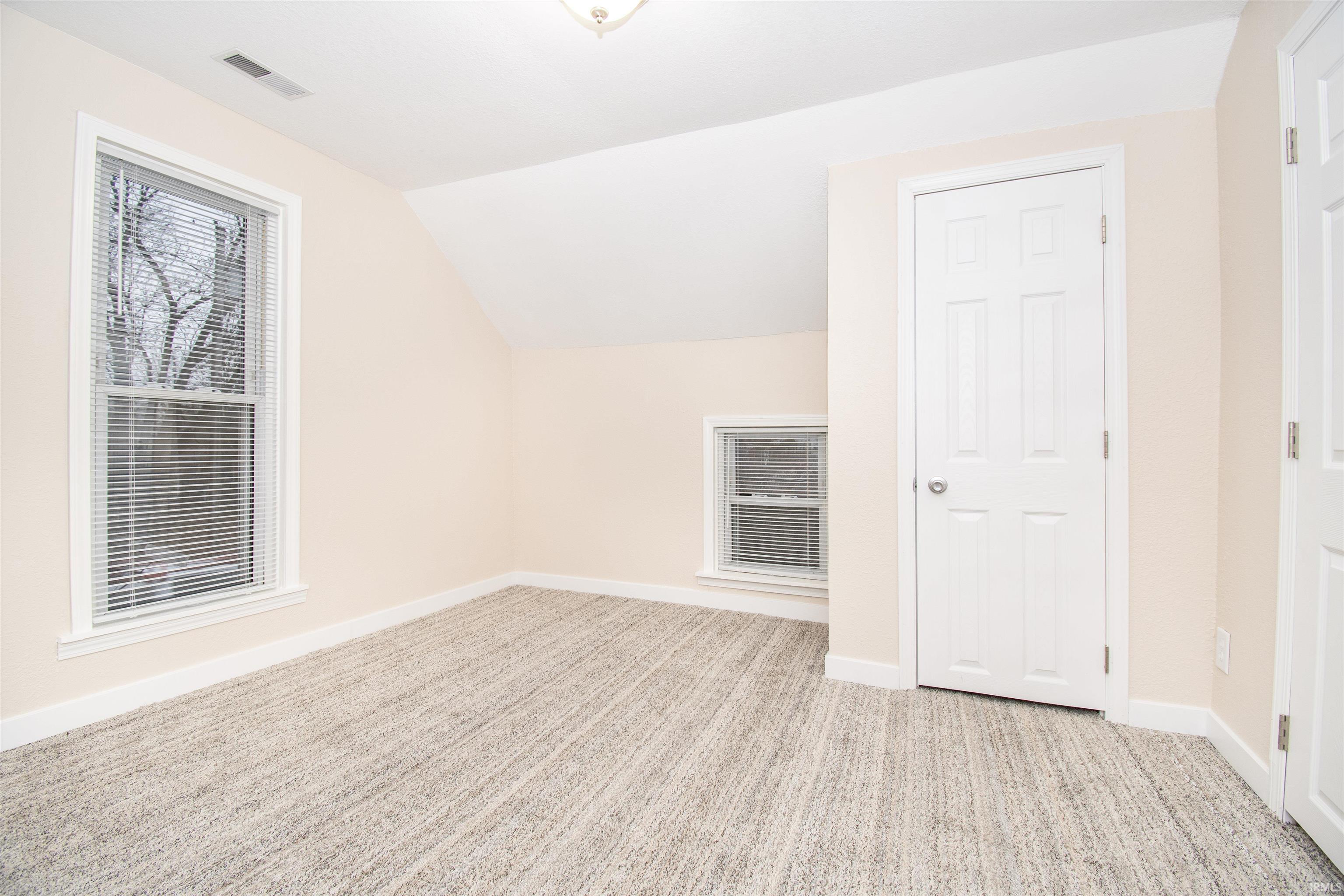 Bonus room featuring light colored carpet and vaulted ceiling