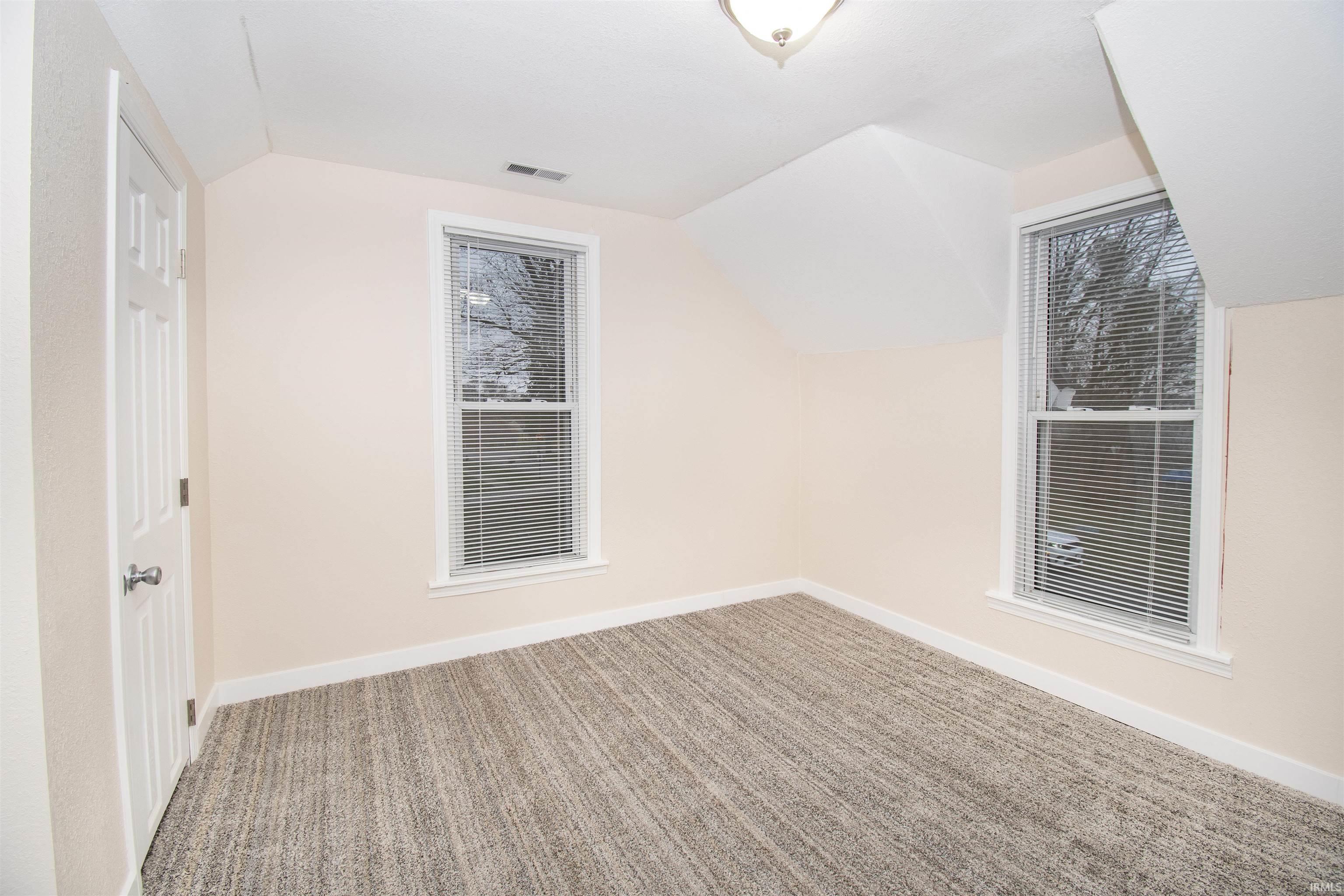 Spare room with vaulted ceiling and light colored carpet
