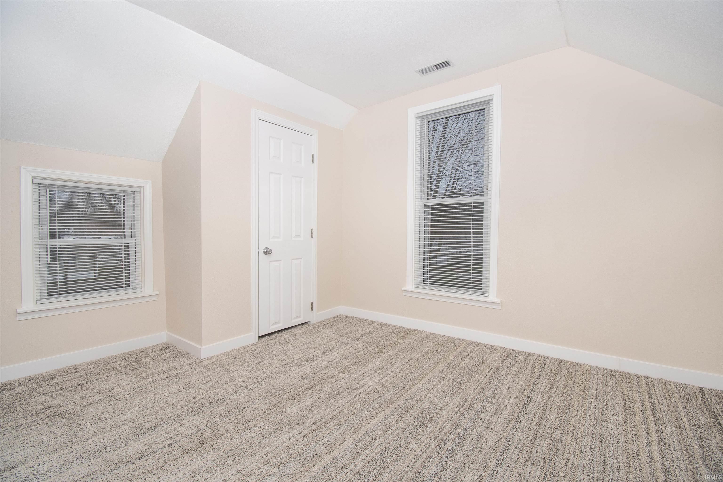 Bonus room with vaulted ceiling and light colored carpet