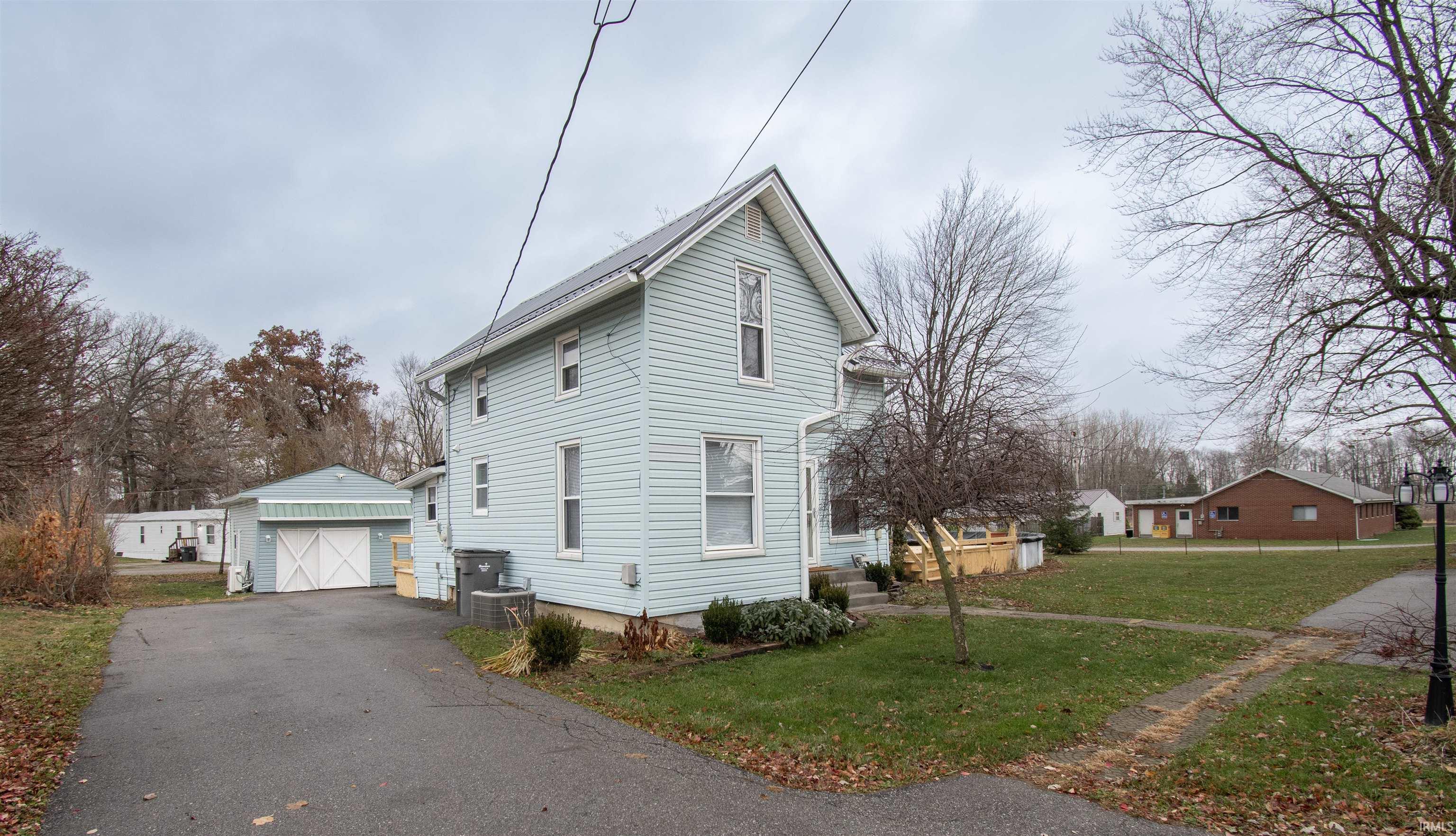 View of side of property with a yard, a detached garage, an outbuilding, and asphalt driveway