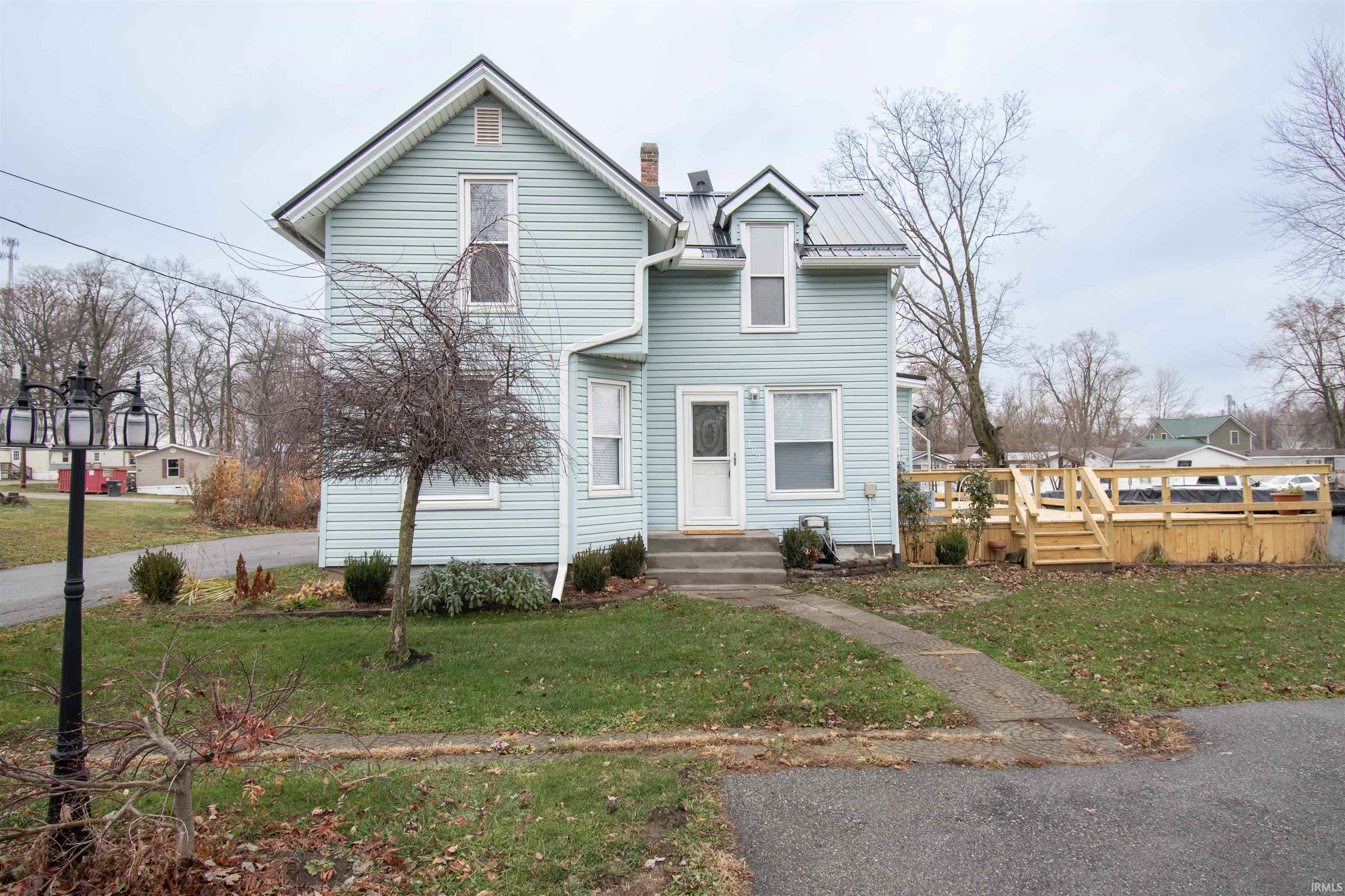 View of front of home with a front yard, a chimney, a metal roof, and a standing seam roof
