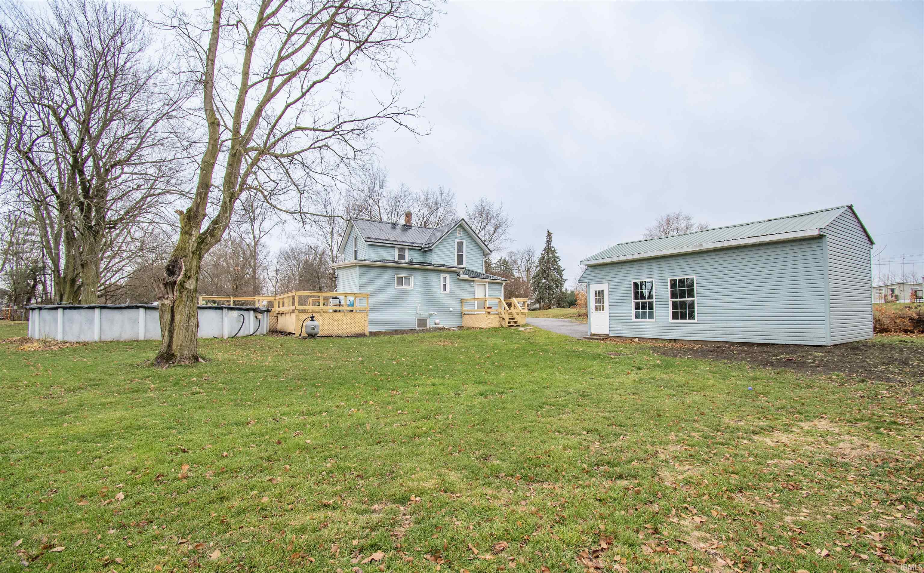 Back of house with an outdoor structure, a lawn, an outdoor pool, and a deck