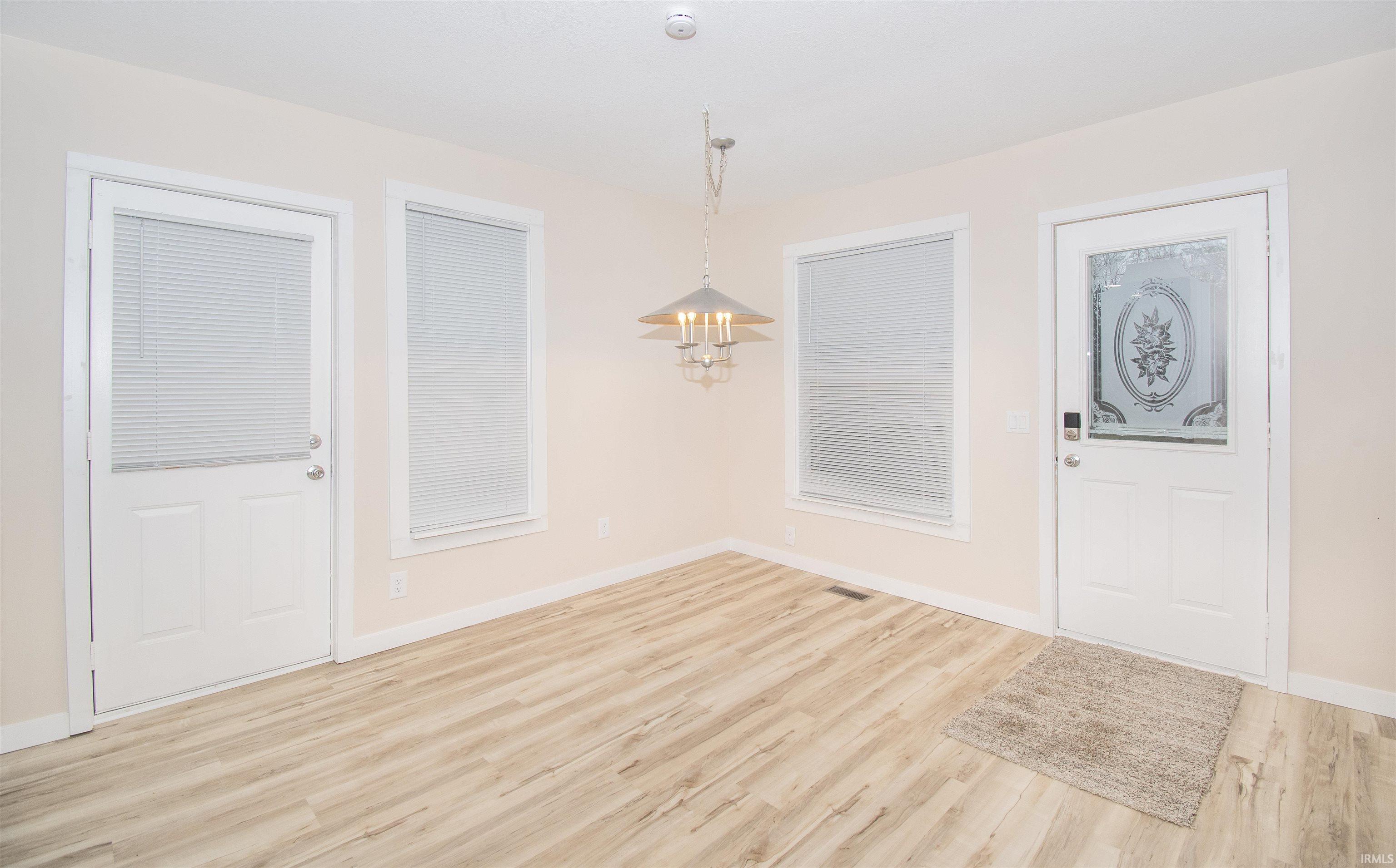 Foyer entrance with light wood-style floors and a chandelier