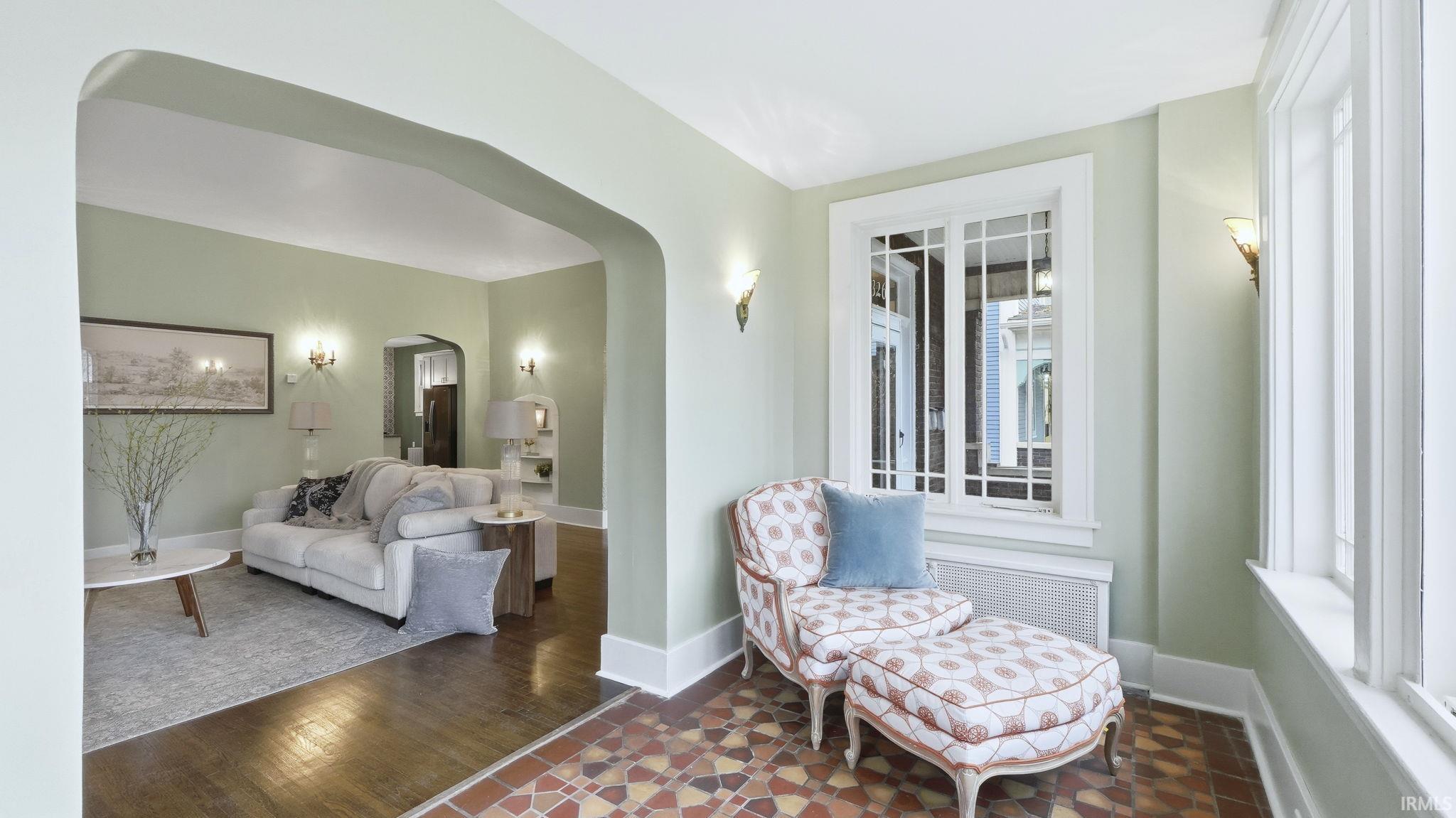 Living area featuring arched walkways, radiator, and dark wood finished floors