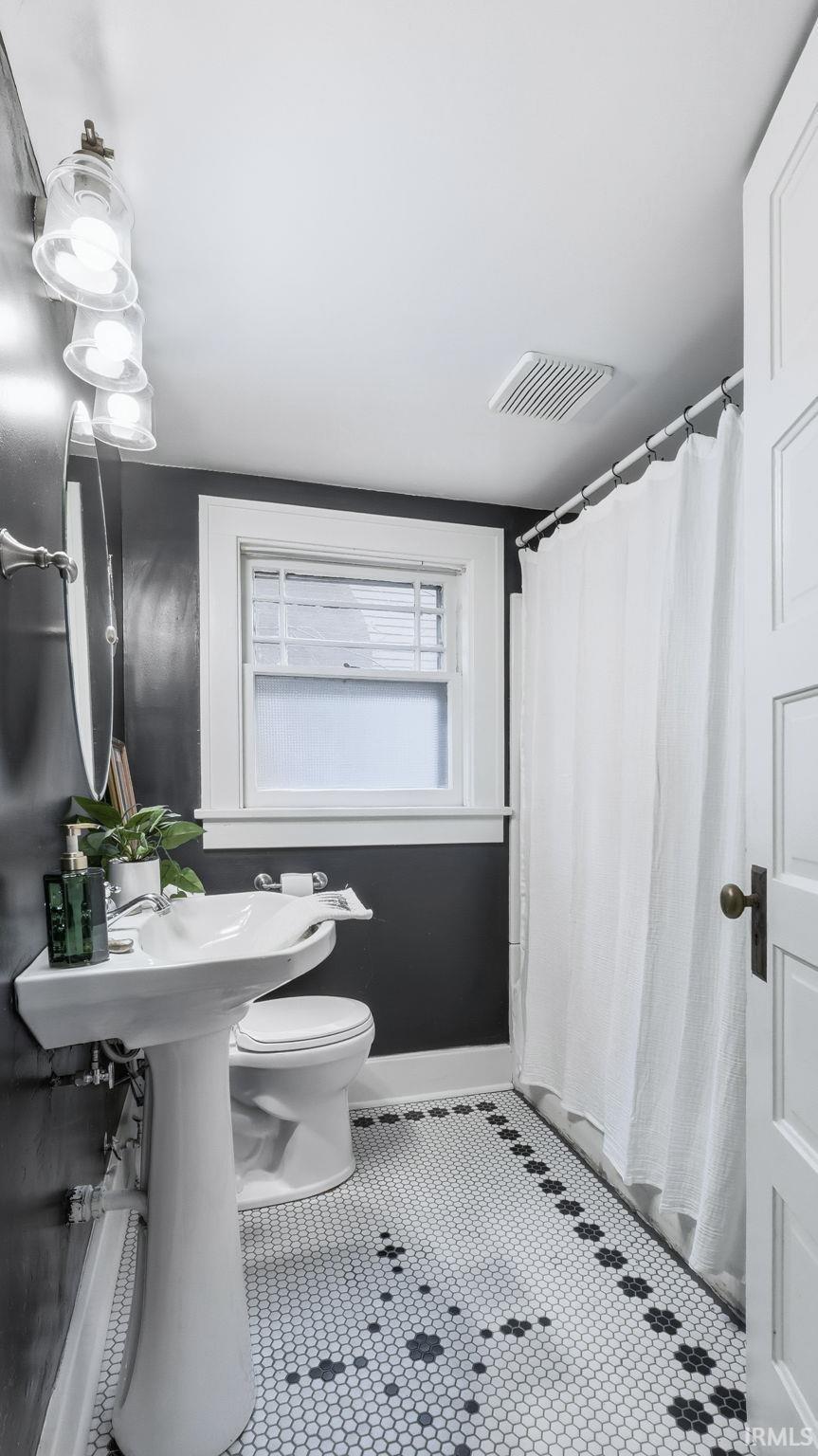 Bathroom with a shower with curtain and tile patterned flooring