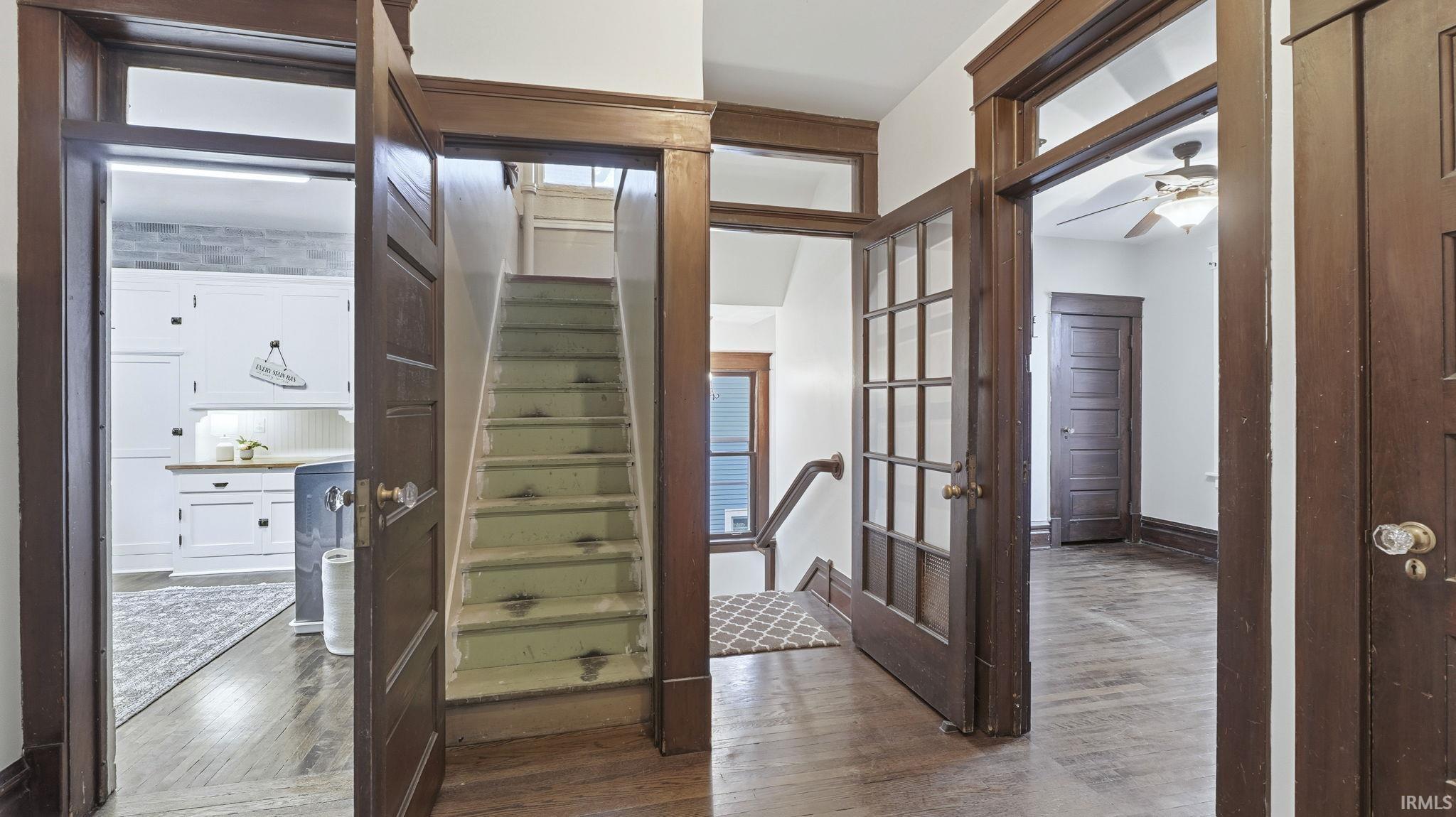 Stairway with wood-type flooring, ceiling fan, and french doors
