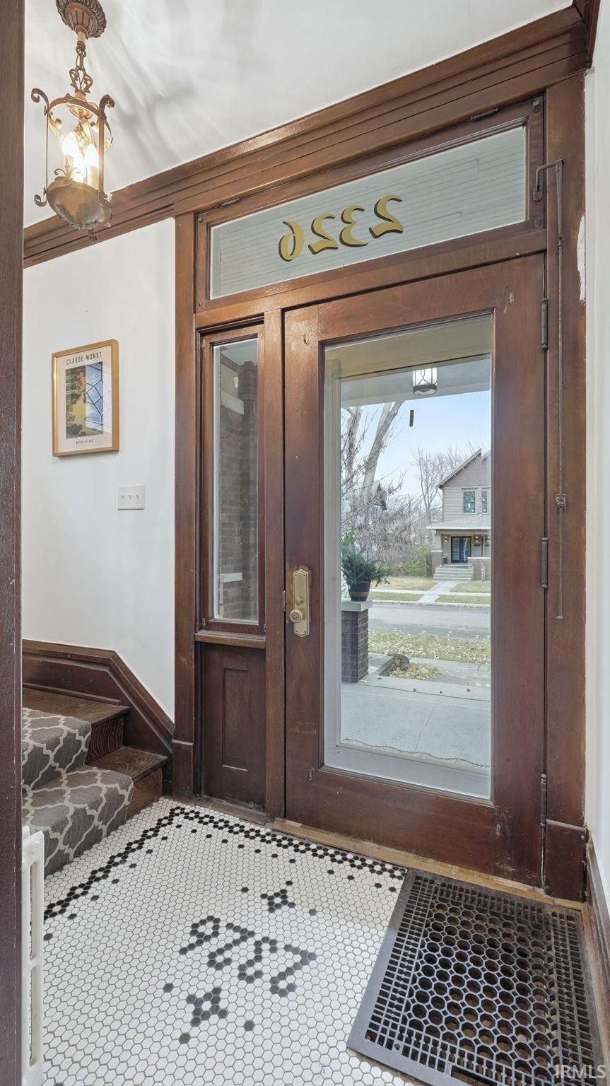 Foyer entrance featuring inlaid floor details, tile patterned floors, and a chandelier