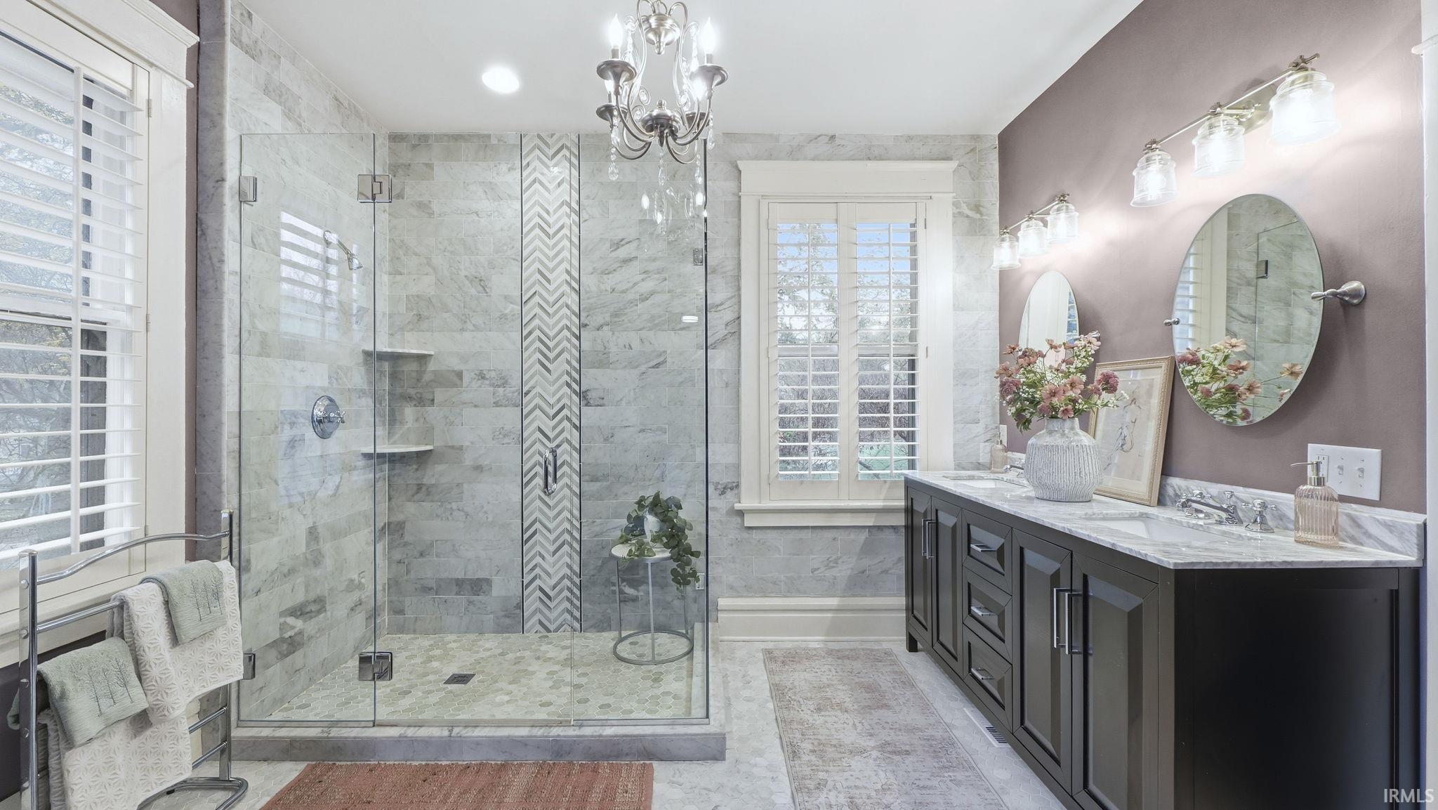 Bathroom featuring double vanity, a shower stall, and a chandelier