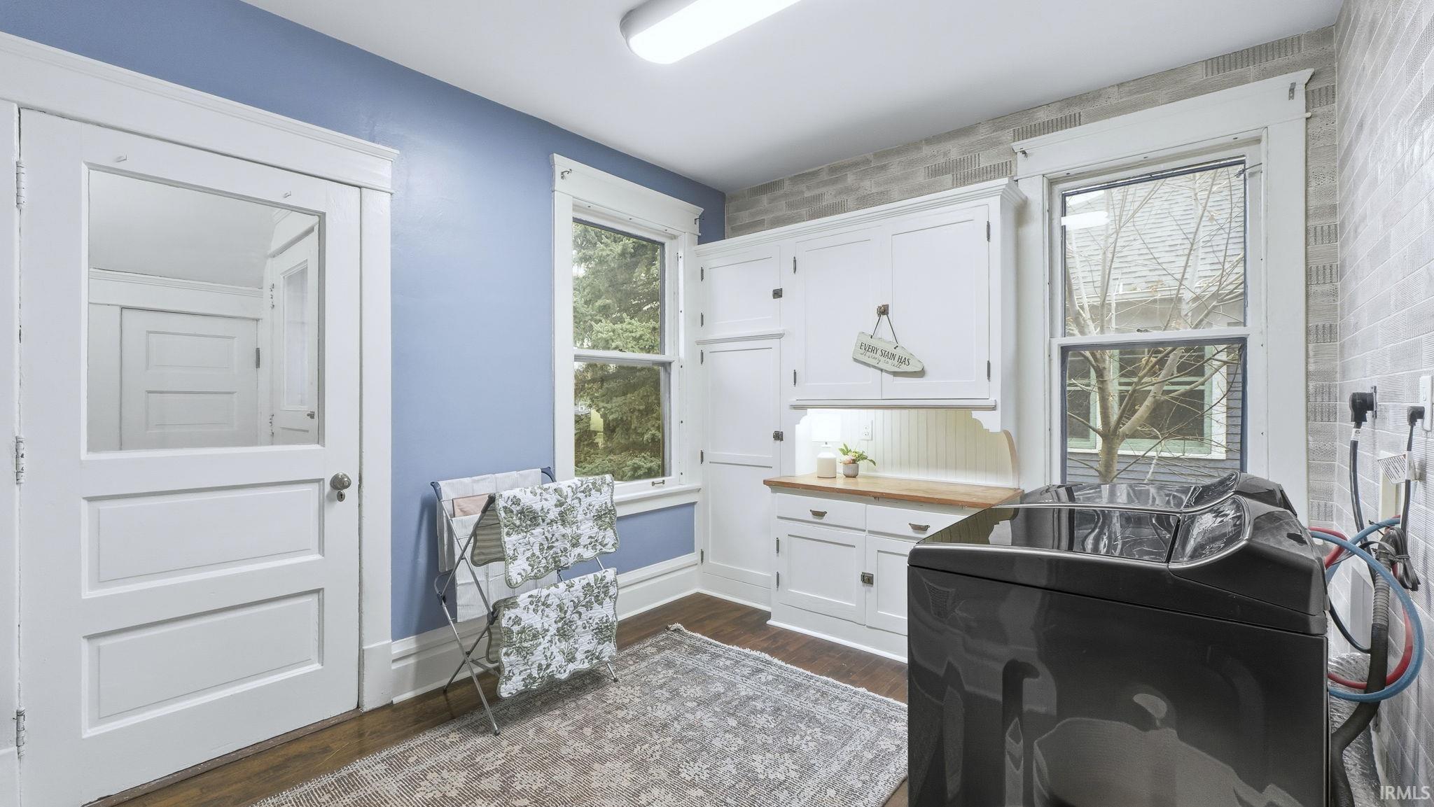 Laundry room featuring dark wood-type flooring and cabinet space