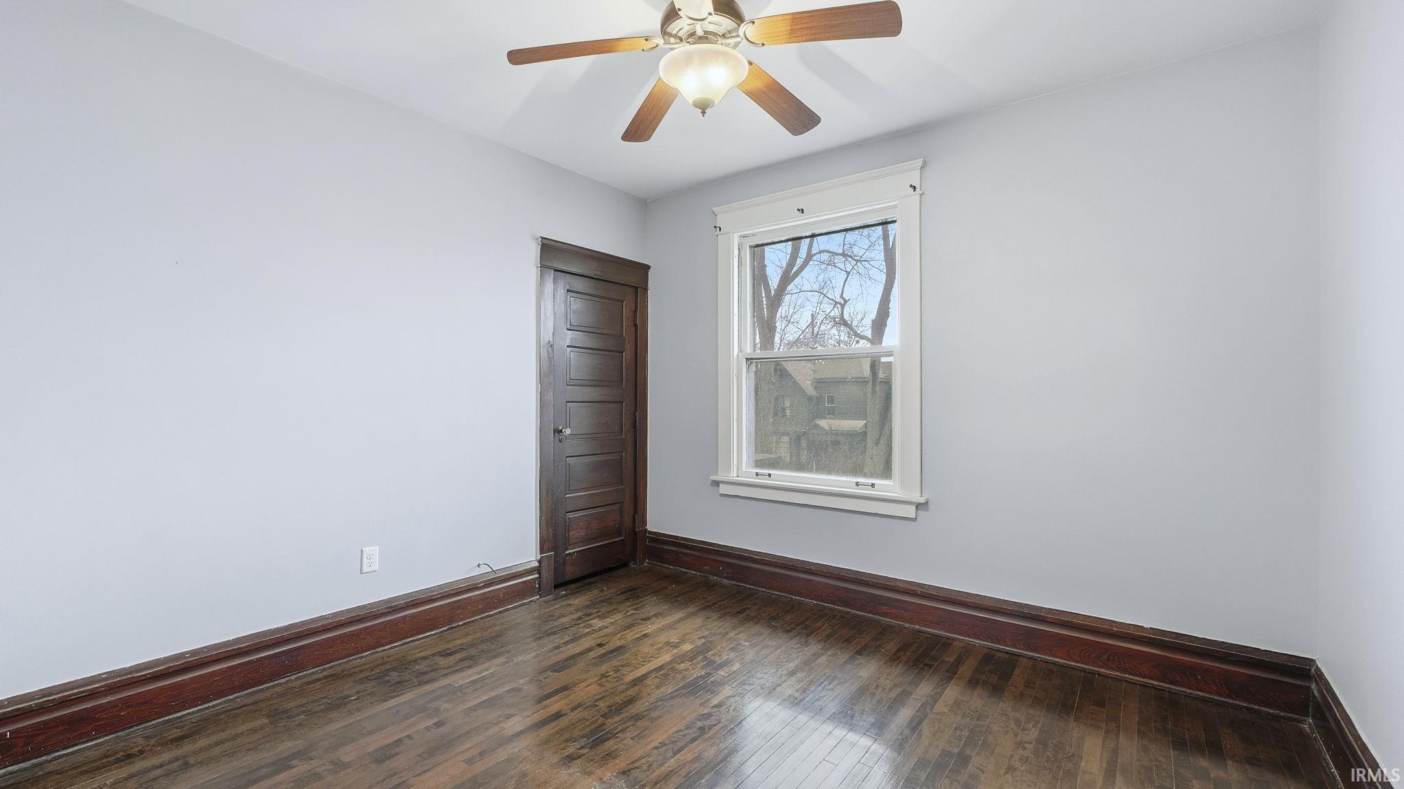 Unfurnished room with dark wood-style floors and a ceiling fan