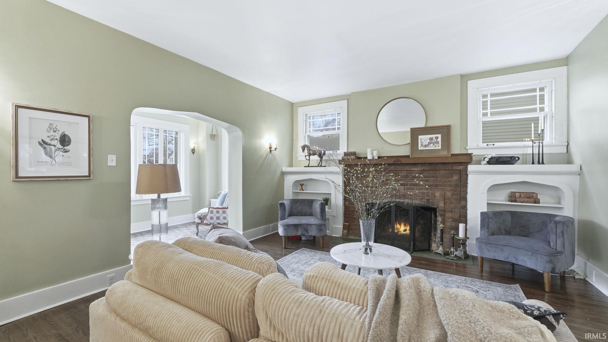 Living room featuring wood finished floors, a fireplace, and arched walkways