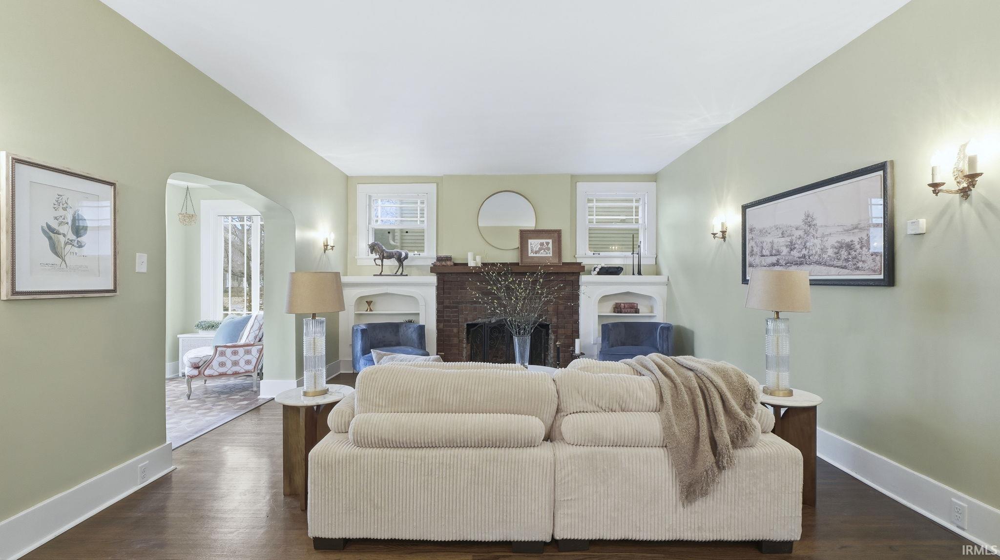Living area featuring a fireplace, dark wood-style flooring, and arched walkways