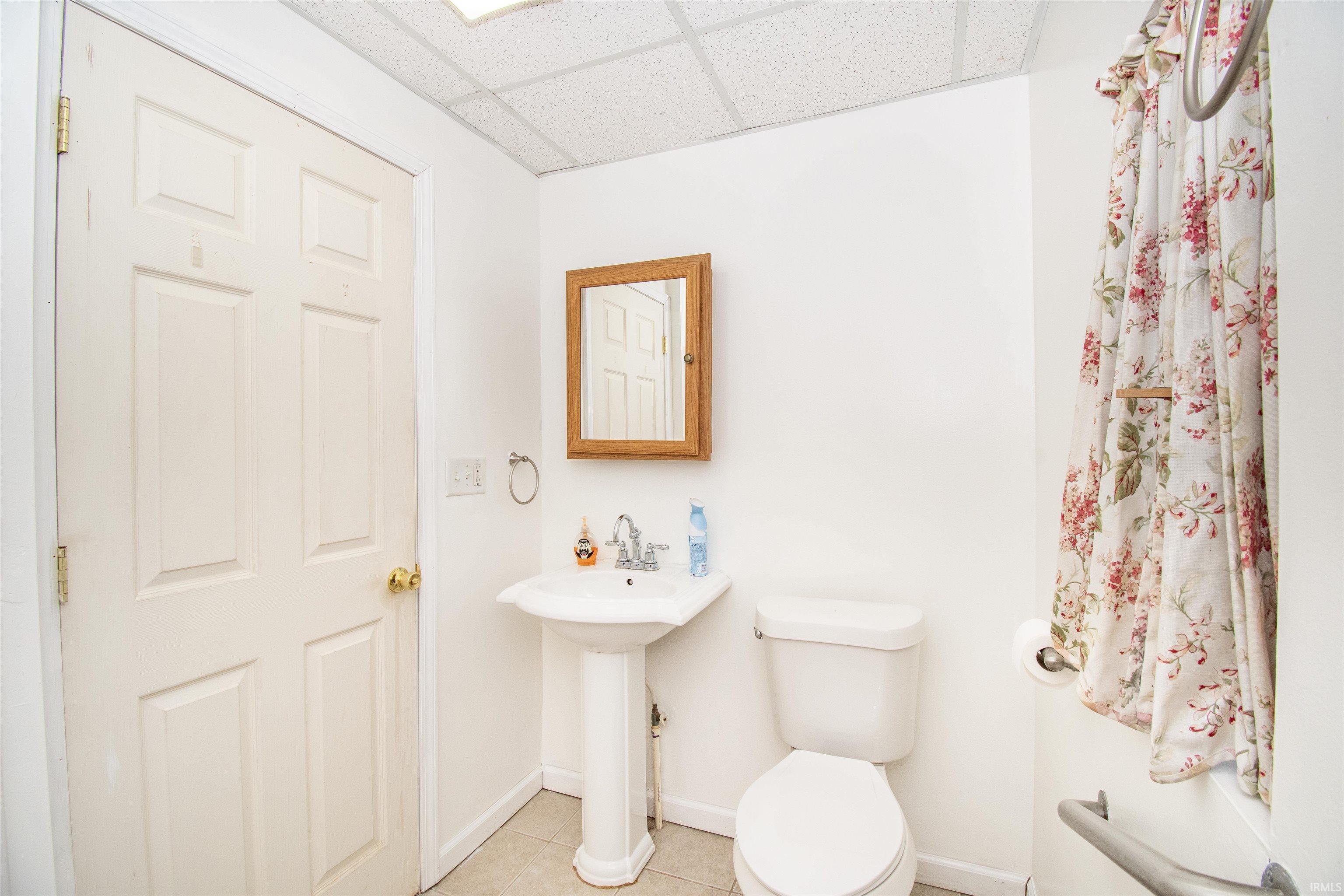 Half bathroom featuring a paneled ceiling and tile patterned flooring