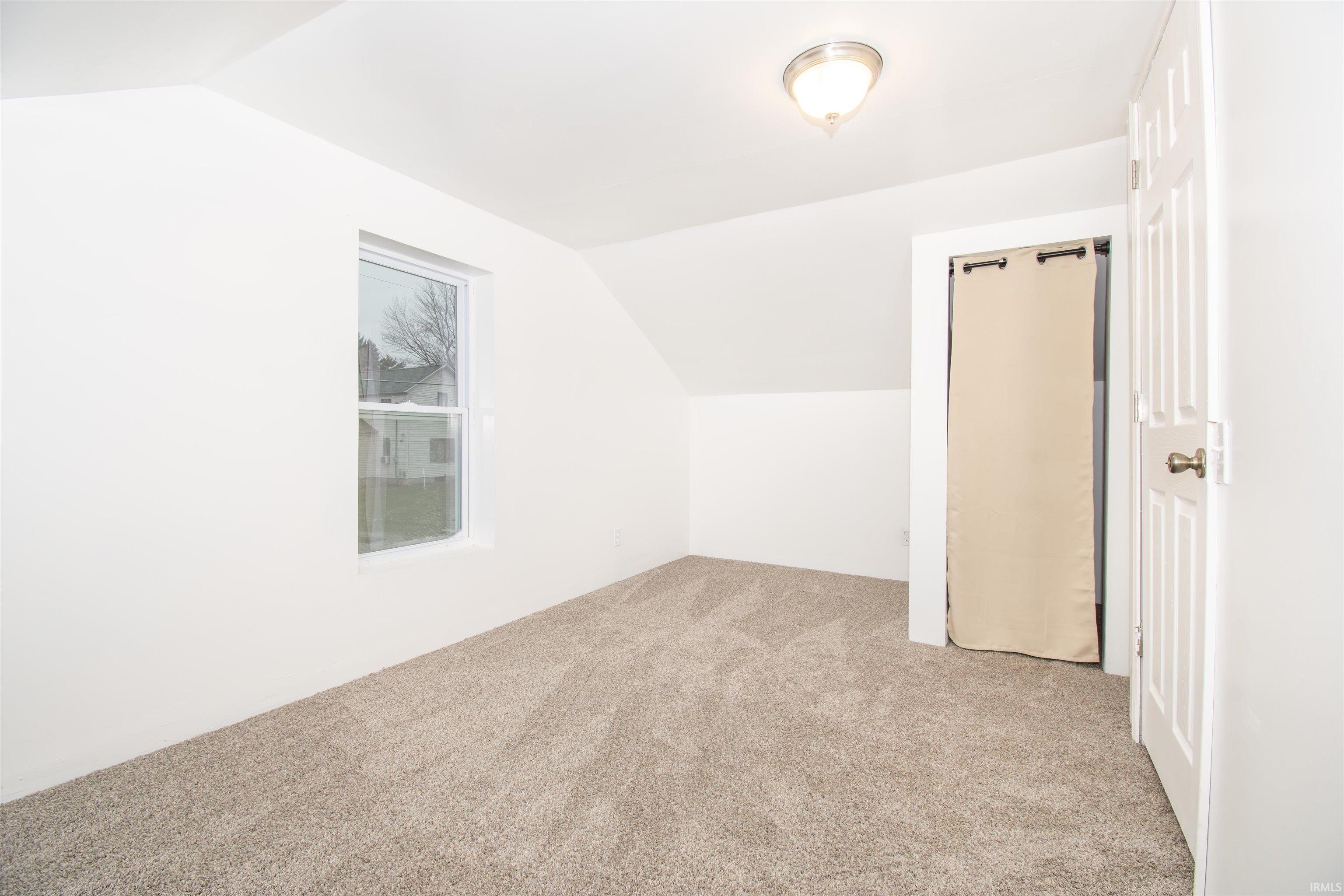 Bonus room featuring lofted ceiling and light carpet