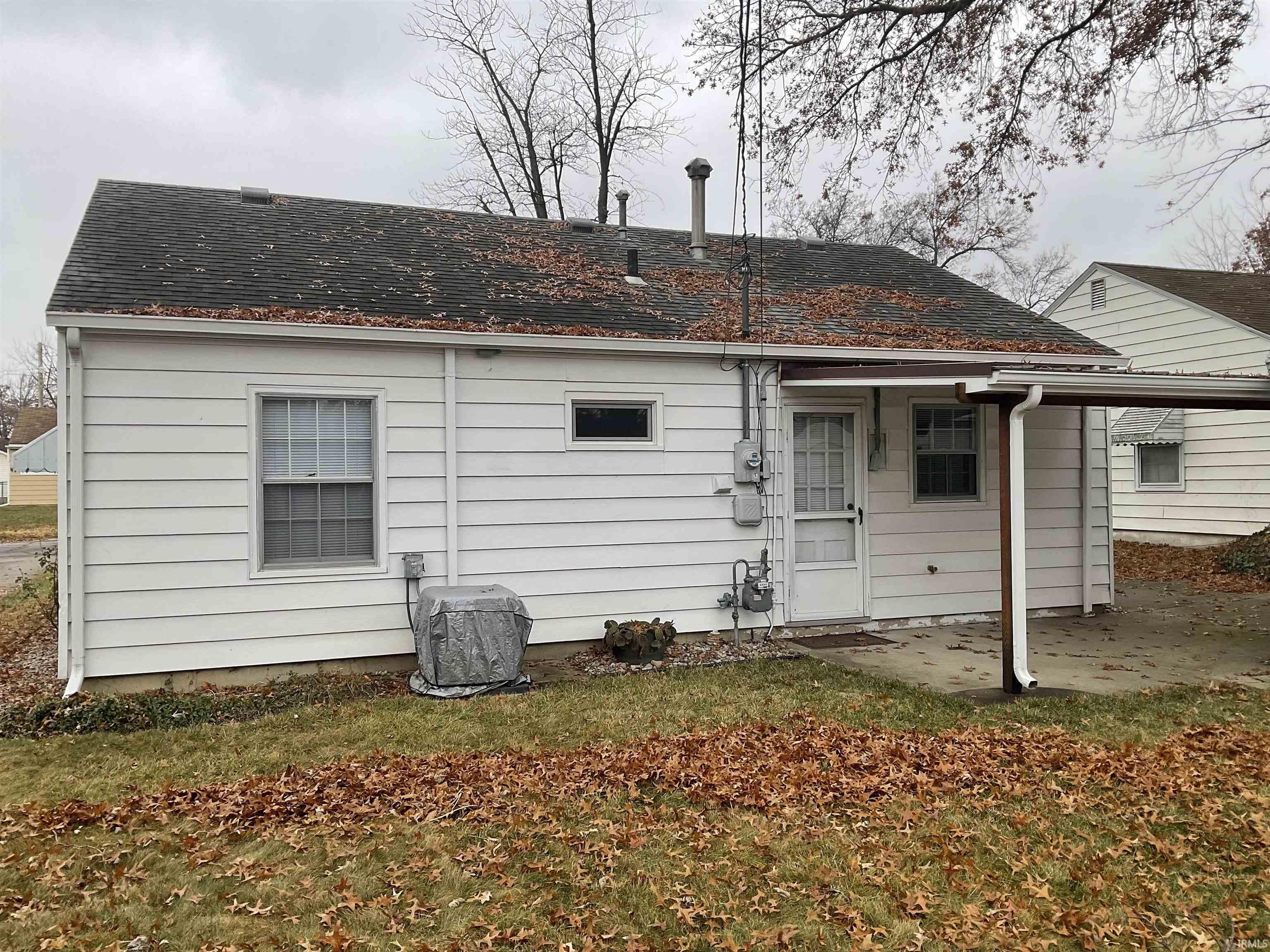 Back of property featuring a patio, a shingled roof, and a lawn